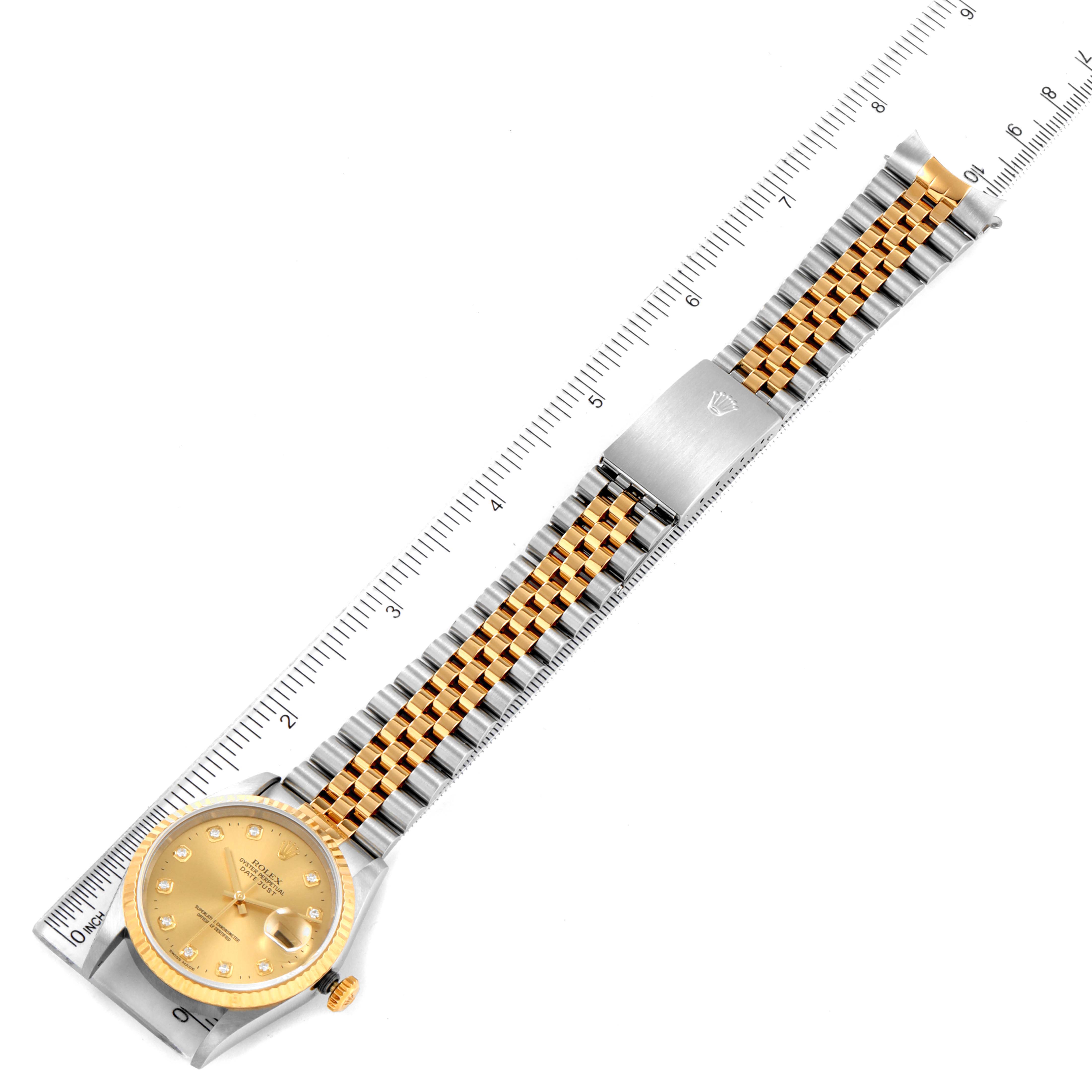 The Rolex Datejust 16233 Men
s Steel and Gold (two tone) Champagne Dial 16233 Men
s Steel and Gold (two tone) Champagne Dial watch is shown from a top-down angle, displaying its face, bezel, and two-toned bracelet beside a ruler.