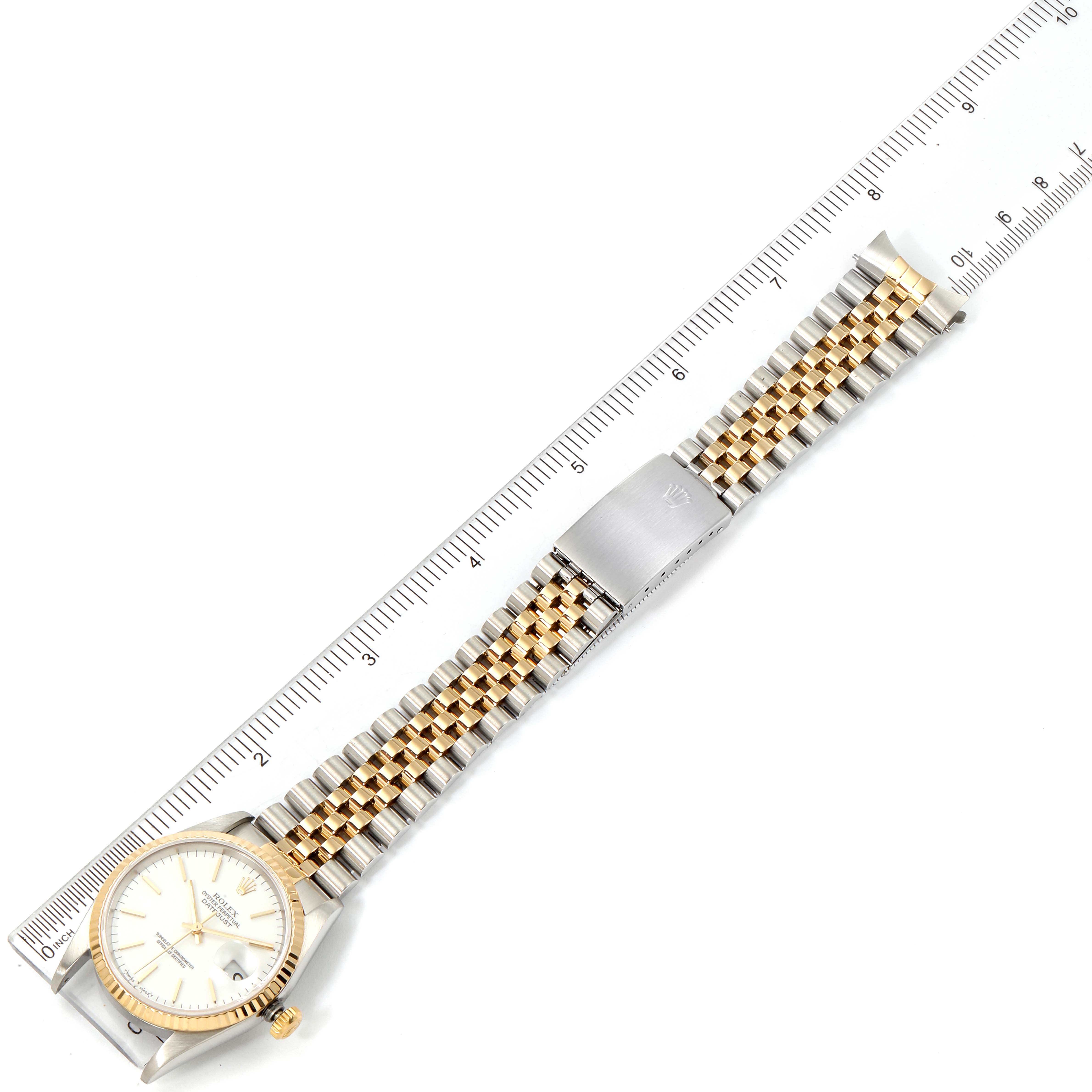 The Rolex Datejust 16233 Men's Steel and Gold (two tone) White Dial 16233 Men's Steel and Gold (two tone) White Dial watch is shown from a top-down view, displaying the face, bezel, and entire bracelet alongside a ruler.