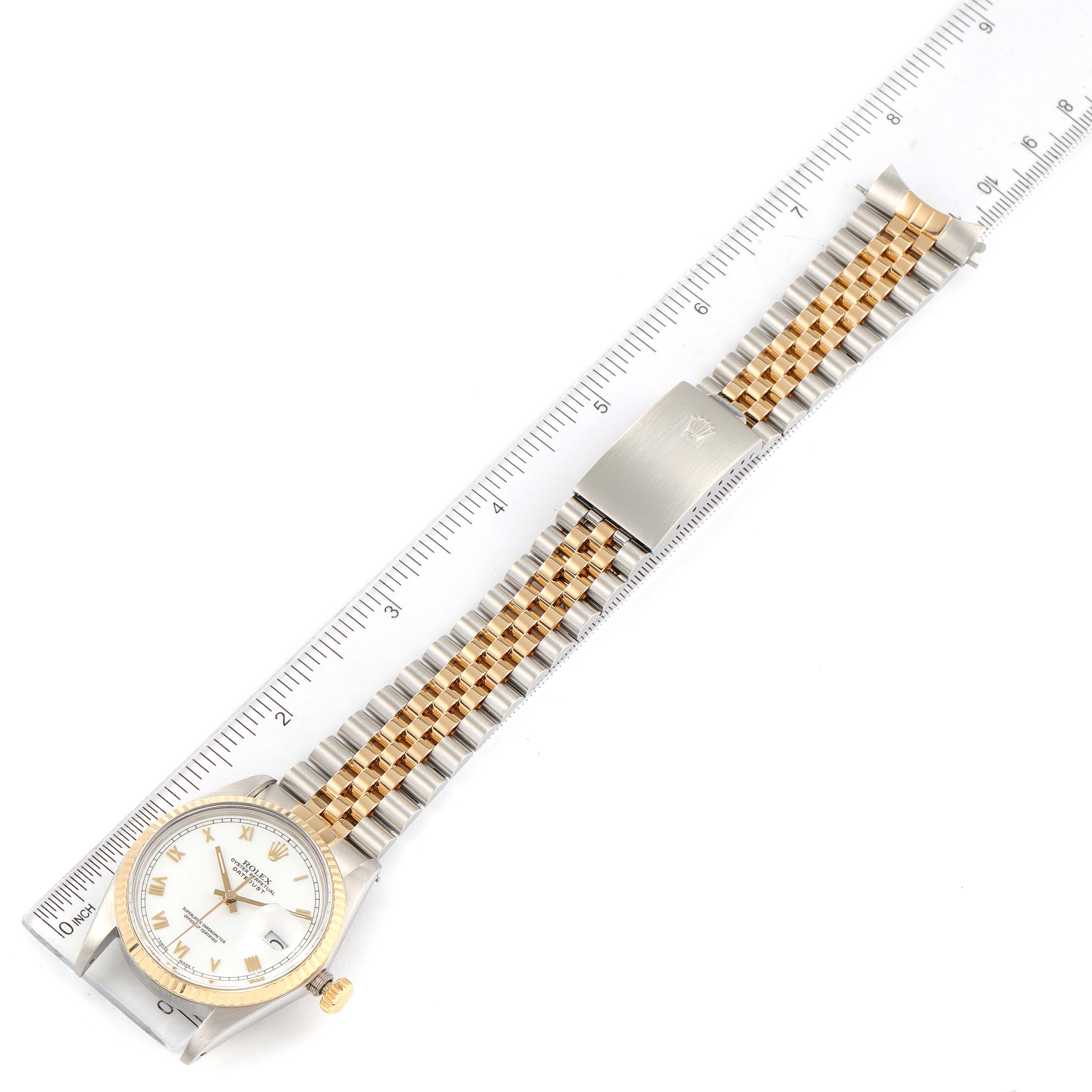 The image shows a Rolex Datejust 16013 Men's Steel and Gold (two tone) White Dial 16013 Men's Steel and Gold (two tone) White Dial watch laid flat beside a ruler, highlighting its dial, bracelet, and clasp.