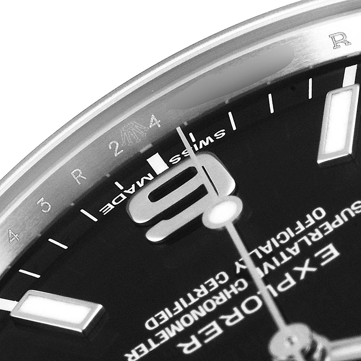 The image shows a close-up of the dial from the Explorer model watch by Rolex, highlighting part of the hour indices and text.