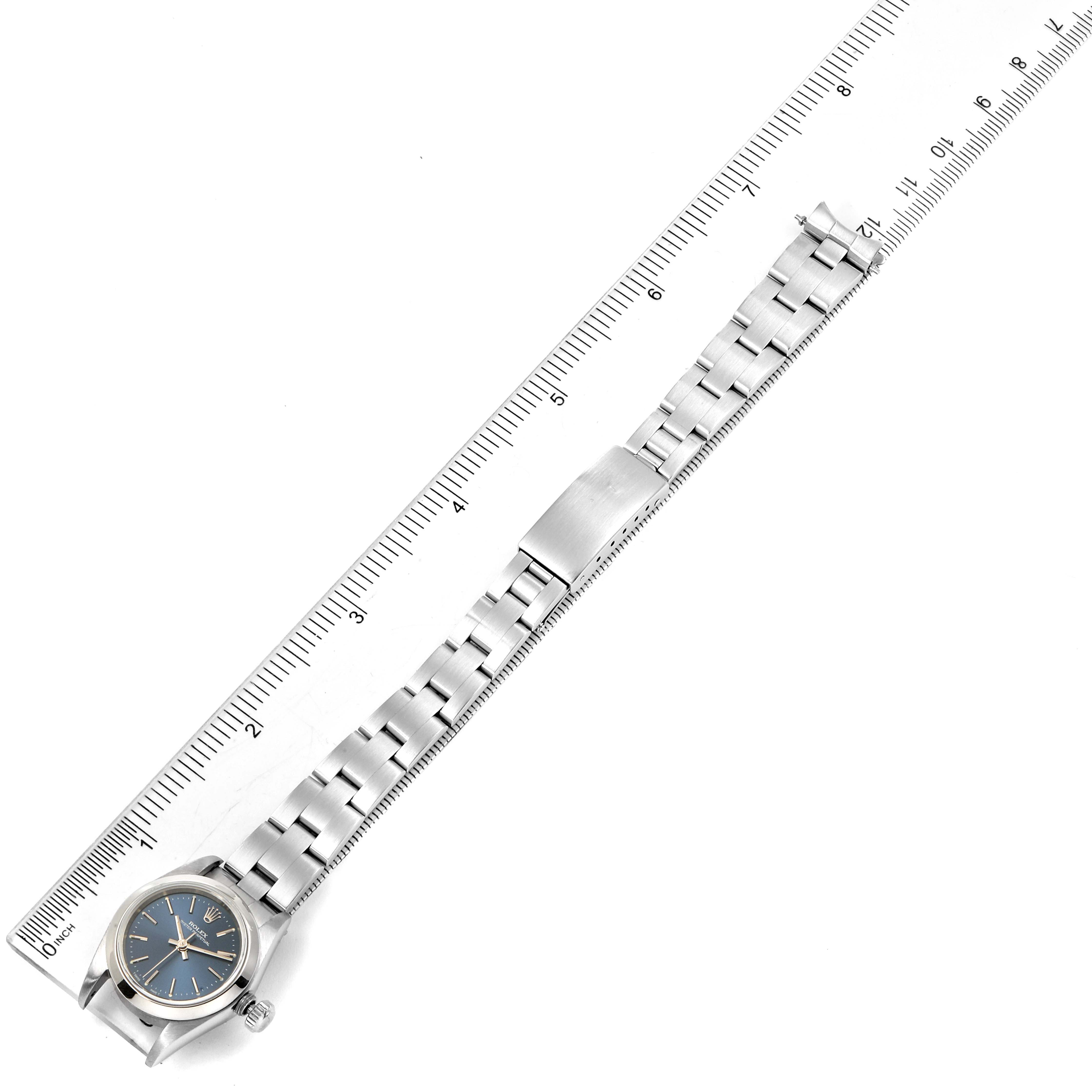 The image shows a Rolex Oyster Perpetual 67180 Women
s Stainless Steel Blue Dial 67180 Women
s Stainless Steel Blue Dial watch laid flat with a ruler measuring its length.
