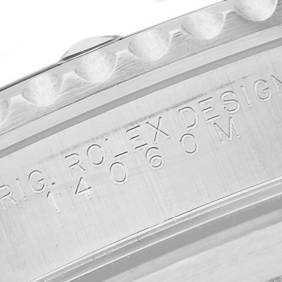 This image shows a close-up of the textured bezel and engraved inner ring of a Rolex Submariner 14060M Men's Stainless Steel Black Dial 14060M Men's Stainless Steel Black Dial watch.