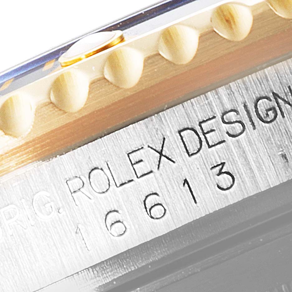 The image shows a close-up of the engraved bezel and case side of a Rolex Submariner 16613 Men
s Steel and Gold (two tone) Blue Dial 16613 Men
s Steel and Gold (two tone) Blue Dial model 16613.