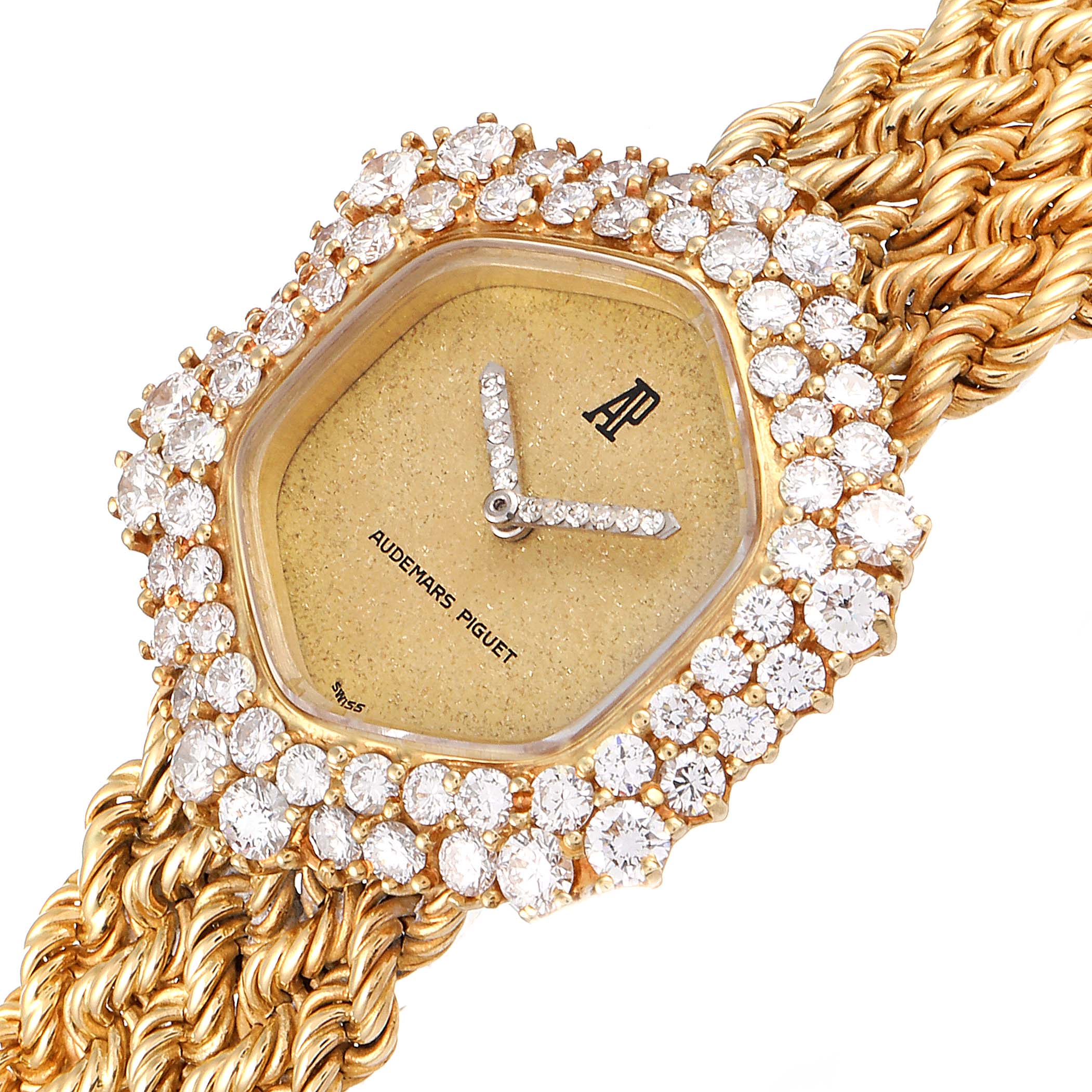 This image shows a close-up of a Vintage Audemars Piguet watch with a gold hexagonal face encrusted with diamonds and a woven bracelet.