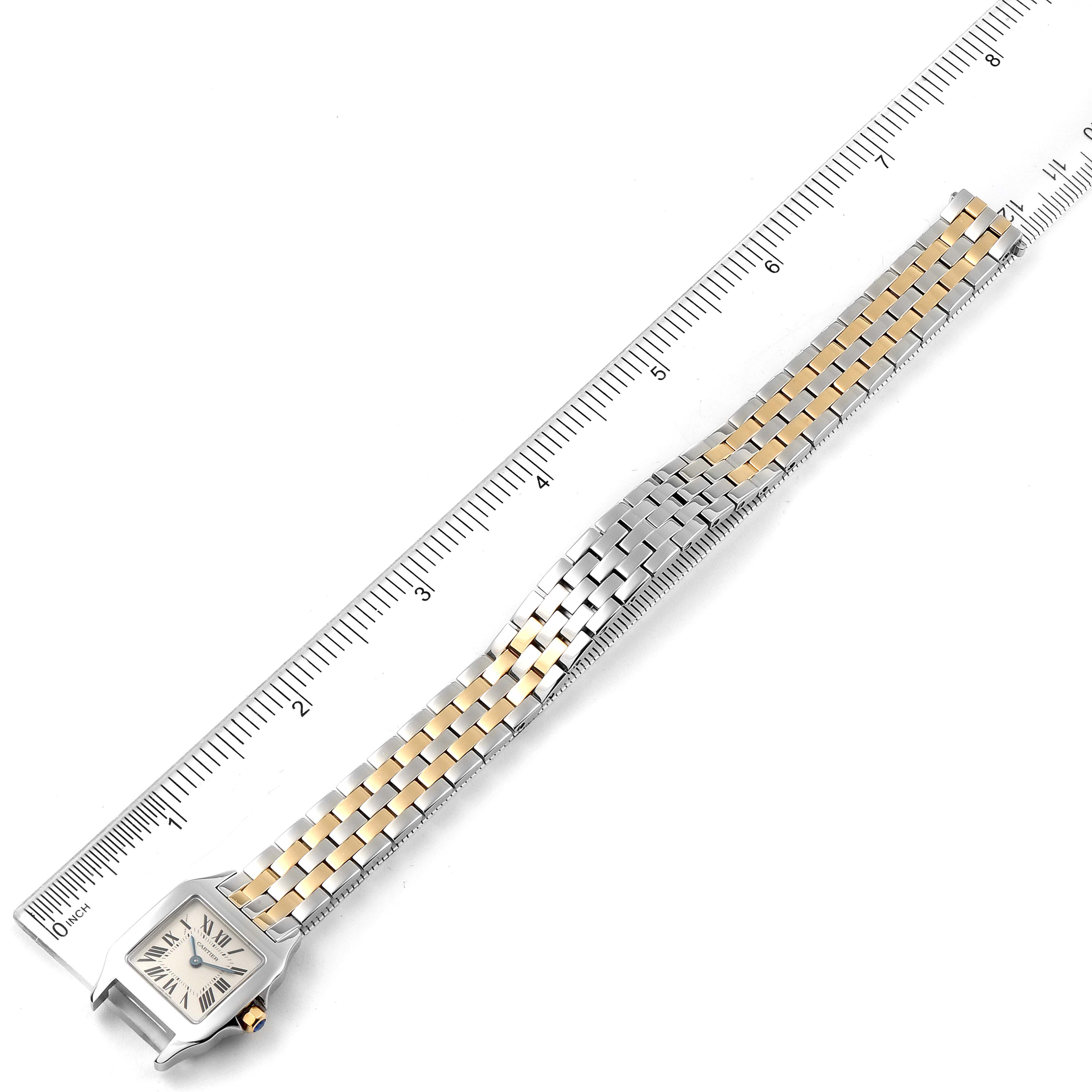 This image shows a top-down view of a Santos Demoiselle model by Cartier, including the watch face and band aligned with a ruler.