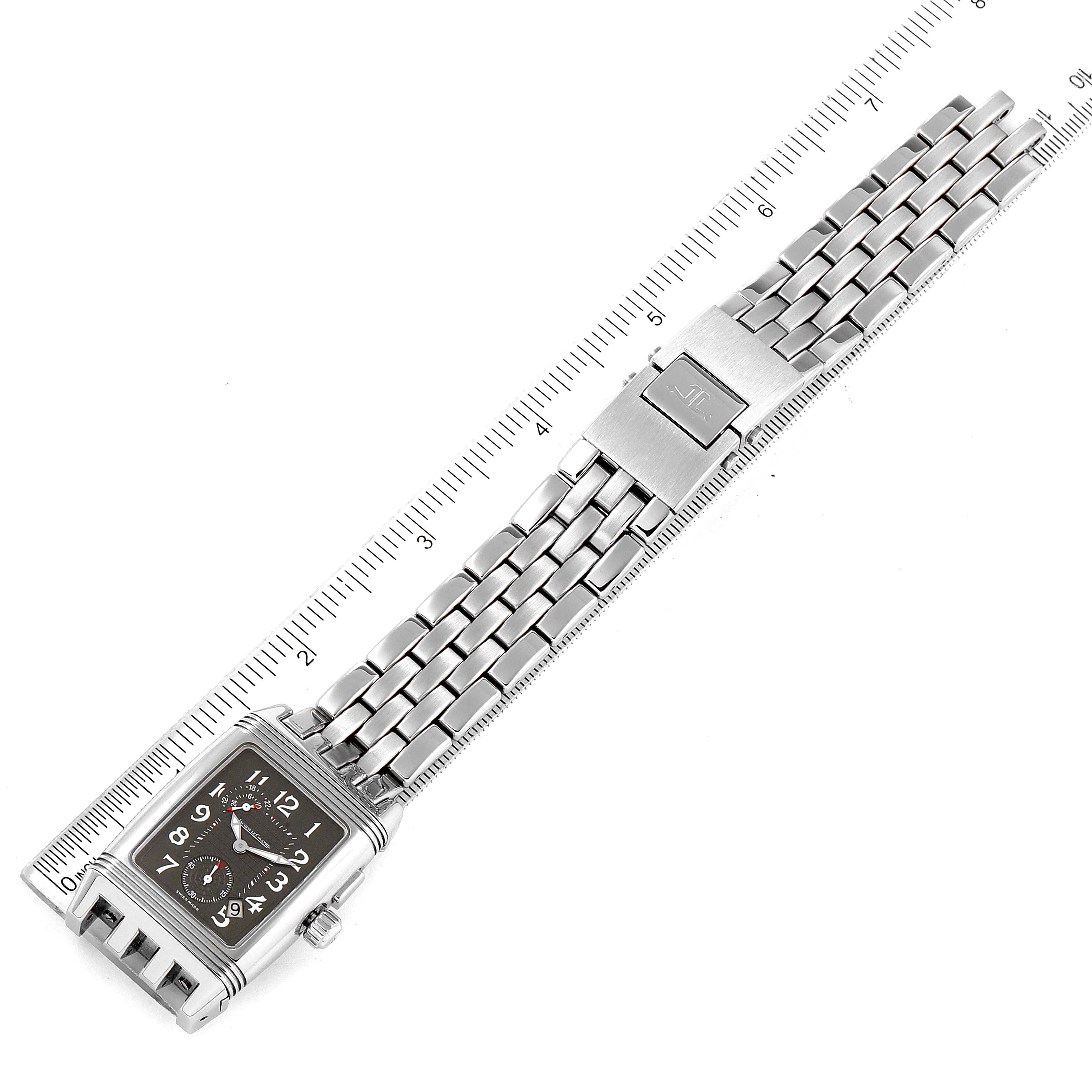 The image shows a Jaeger LeCoultre Reverso 295.8.51 Men
s Stainless Steel Silver Dial 295.8.51 Men
s Stainless Steel Silver Dial watch laid flat alongside a ruler, displaying its rectangular face and metal bracelet.