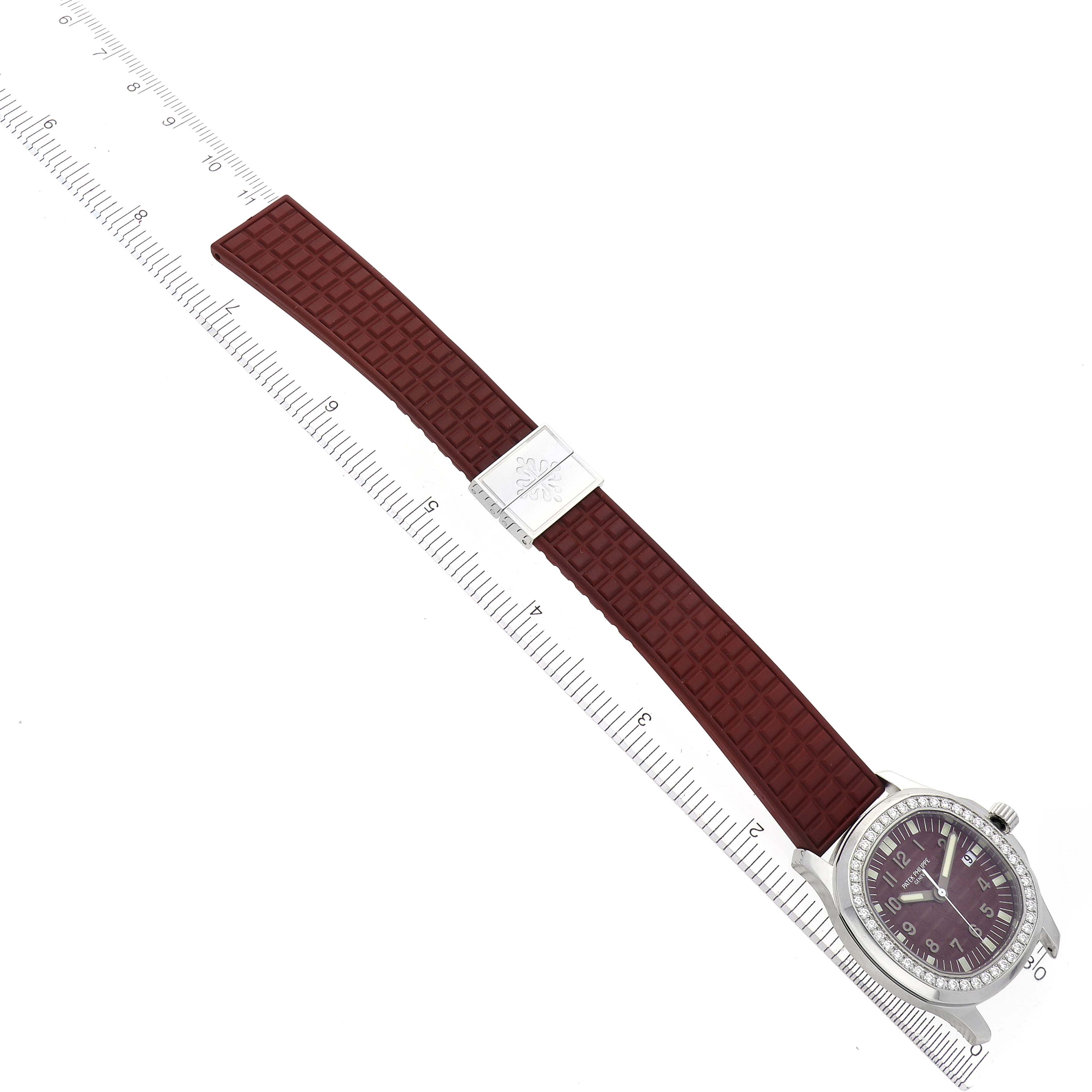 The Patek Philippe Aquanaut 5067A-027 Women's Stainless Steel Red Dial 5067A-027 Women's Stainless Steel Red Dial watch is shown at an angled top view, highlighting its face, bezel, and maroon rubber strap with clasp.