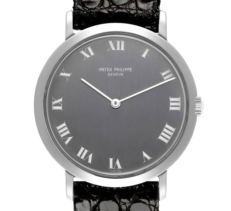 The Patek Philippe Calatrava watch is shown from the front, highlighting its face, Roman numerals, and black leather strap.