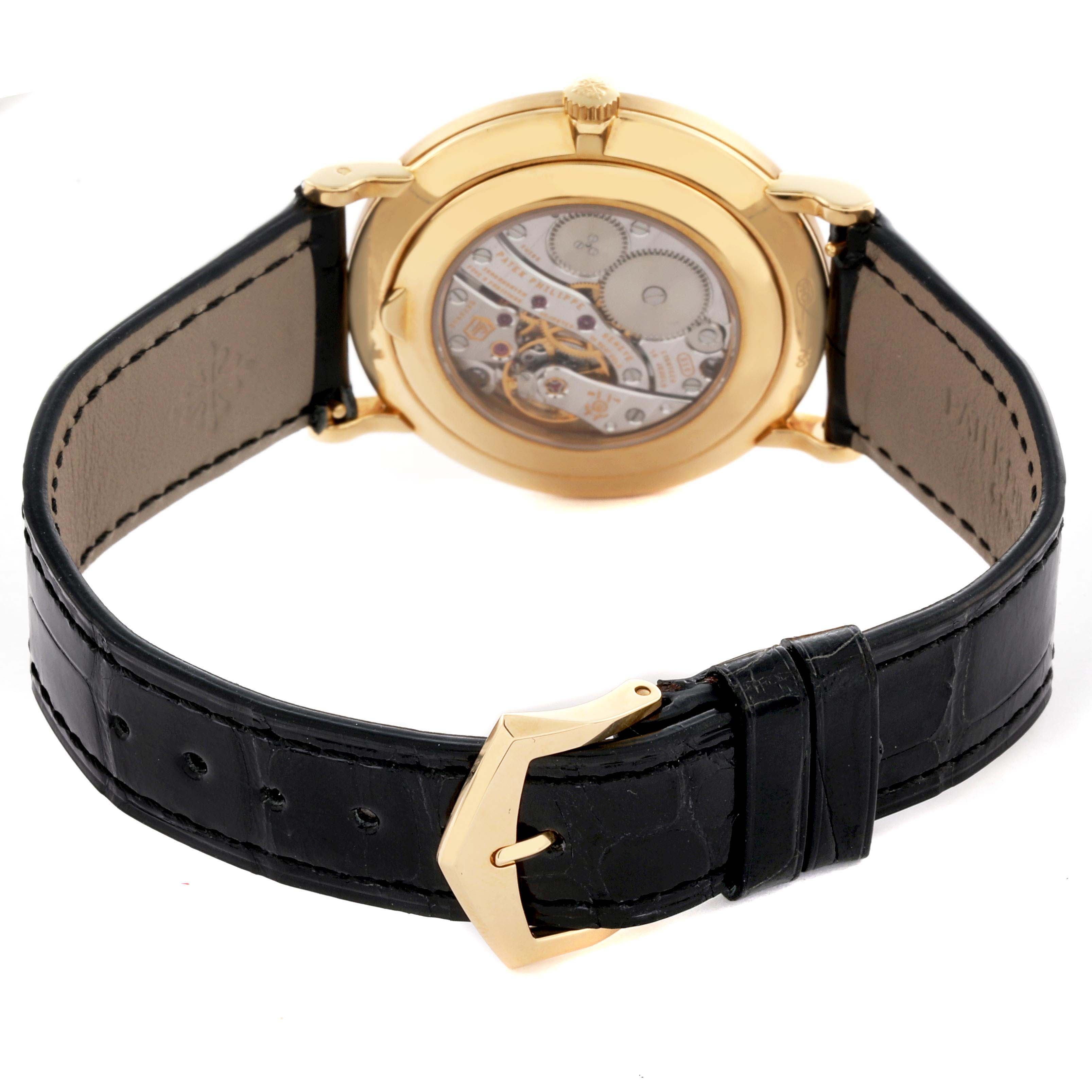 The image shows the back view of a Patek Philippe Calatrava 5119J-001 Men's Yellow Gold White Dial 5119J-001 Men's Yellow Gold White Dial watch, highlighting the movement and black leather strap with a gold buckle.