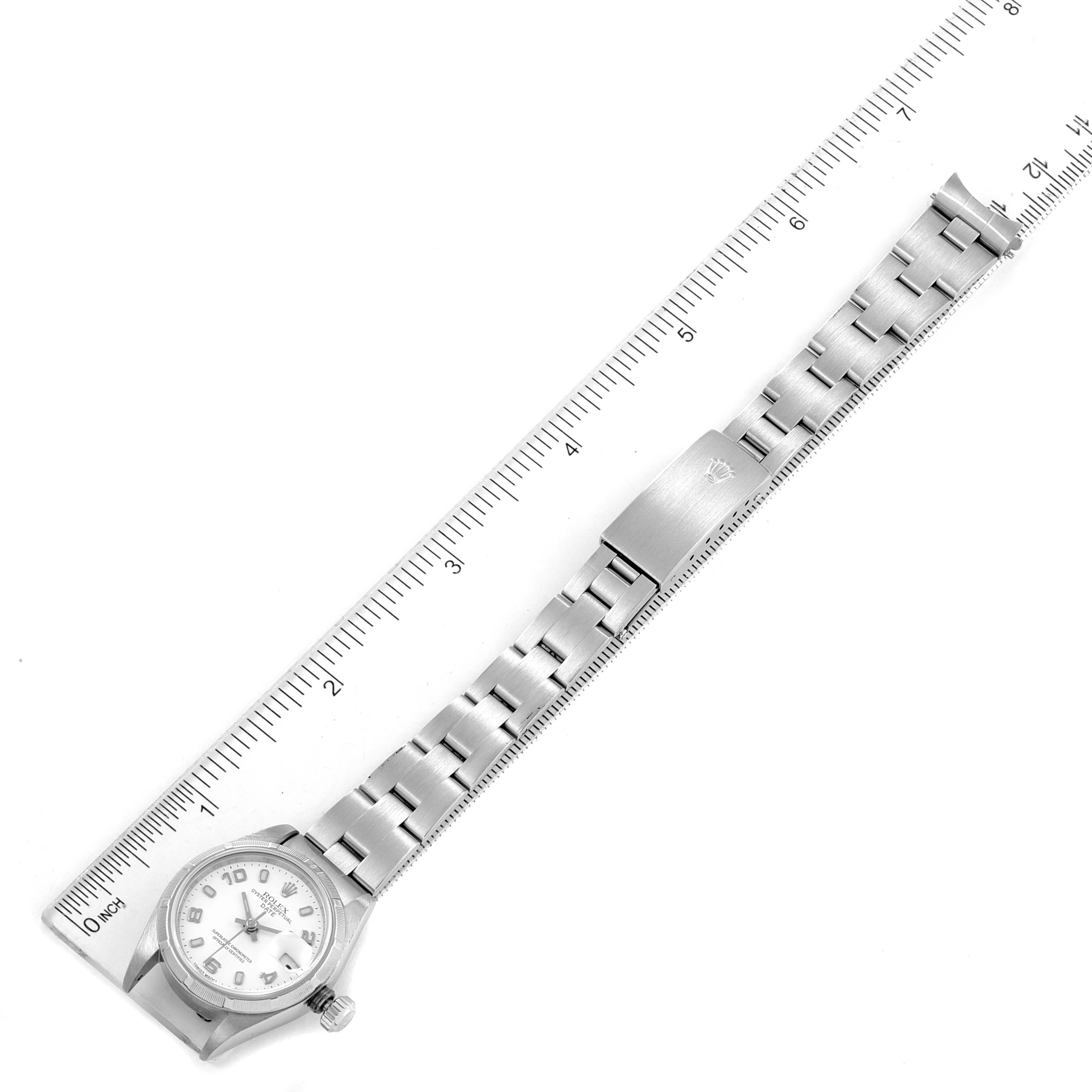 The image shows the front view of a Rolex Date 69190 Women's Stainless Steel White Dial 69190 Women's Stainless Steel White Dial watch, including the dial, bracelet, and clasp alongside a ruler for scale.