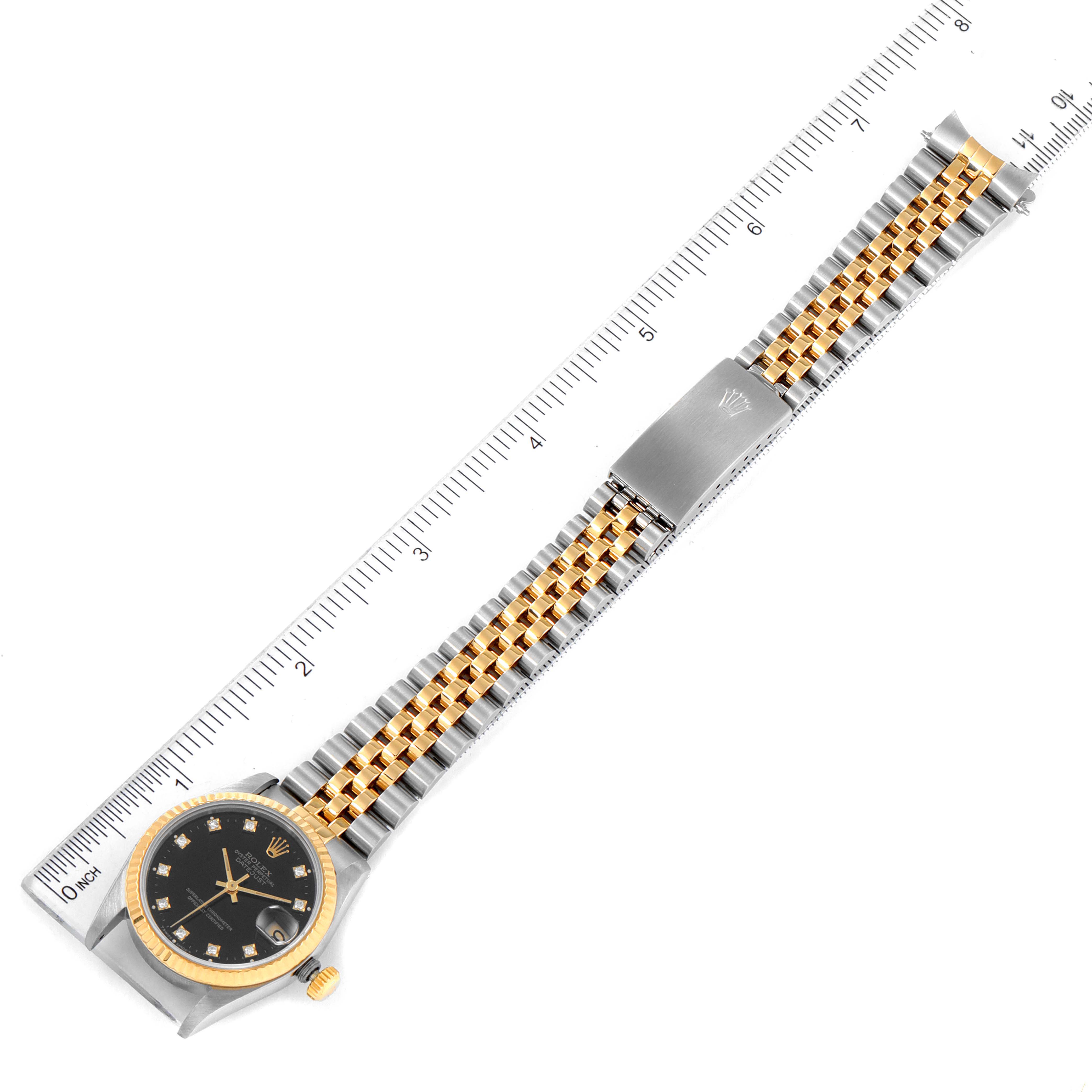 The image shows a Mid-Size Rolex watch positioned flat with a measuring ruler for scale, displaying its bracelet, dial, and clasp.