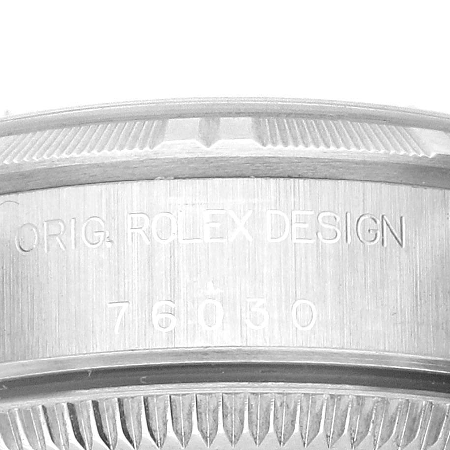 The image shows a close-up of the side of a Rolex Oyster Perpetual 76030 Women's Stainless Steel Black Dial 76030 Women's Stainless Steel Black Dial watch focusing on the engraved serial number and "ROLEX DESIGN."
