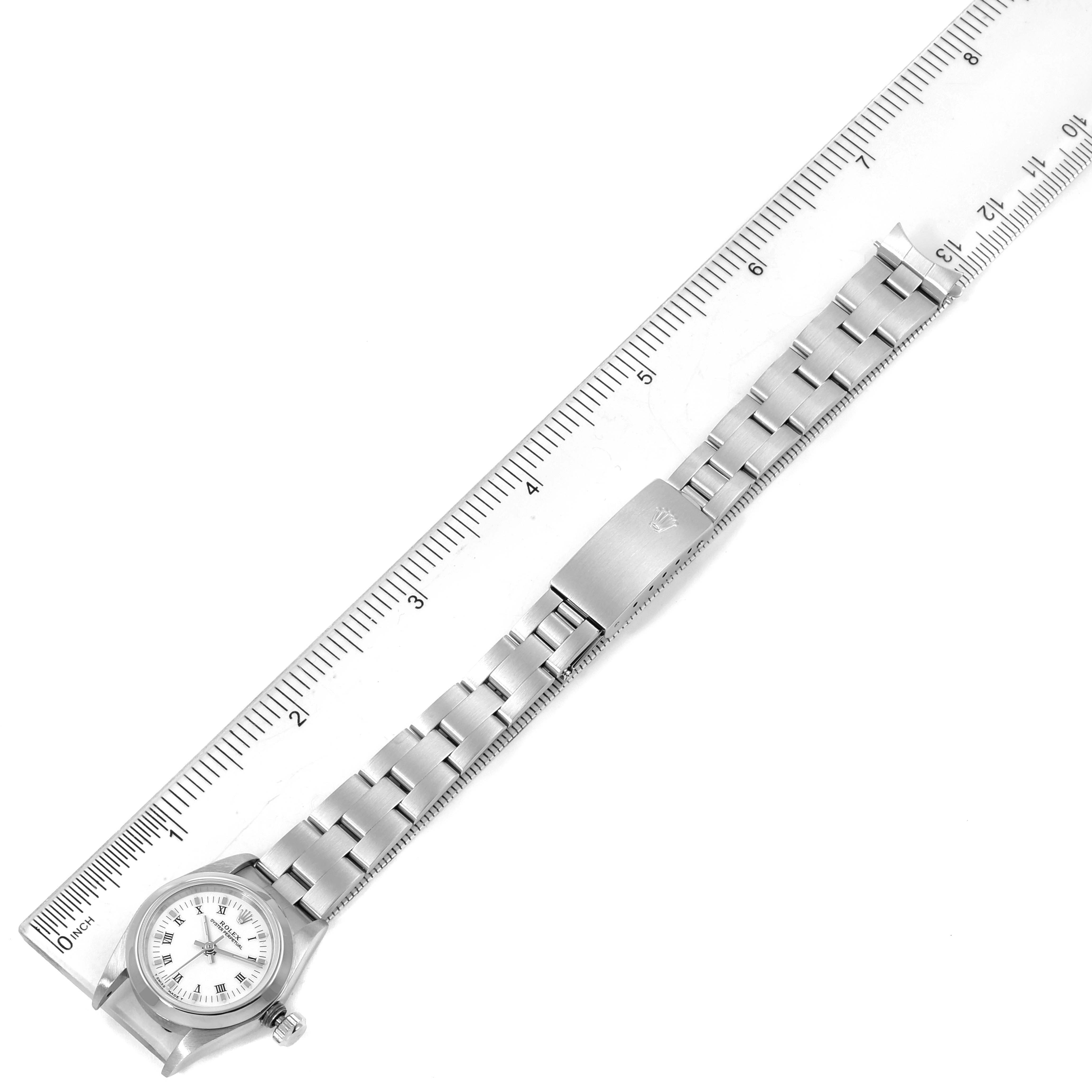 The image shows a top-down view of a Rolex Oyster Perpetual 67180 Women's Stainless Steel White Dial 67180 Women's Stainless Steel White Dial watch alongside a ruler.