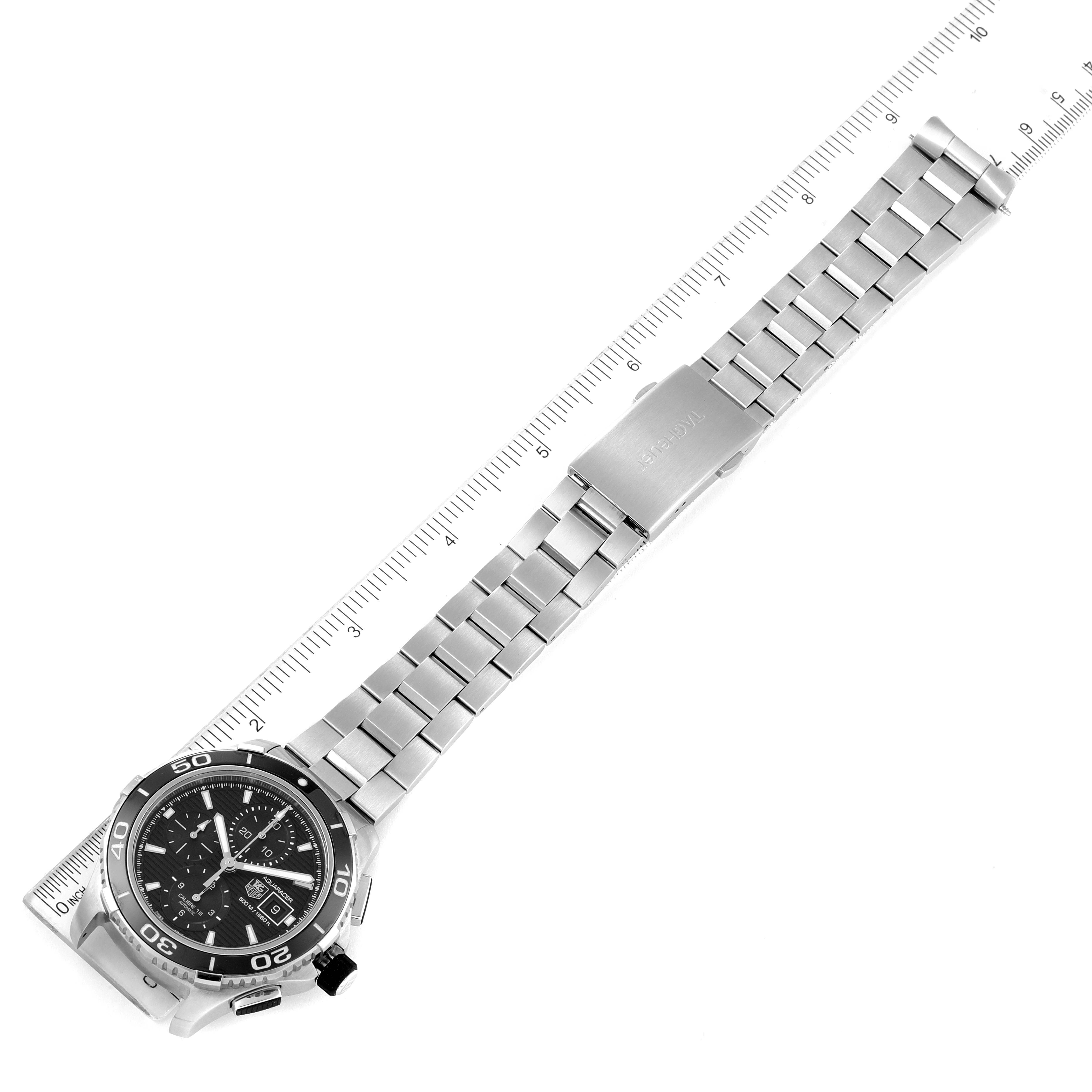 The image shows a top view of a Tag Heuer Aquaracer CAK2110.BA0833 Men
s Stainless Steel Black Dial CAK2110.BA0833 Men
s Stainless Steel Black Dial watch with a metal strap aligned with a ruler.