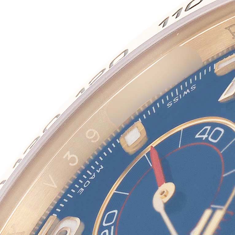 The image shows a close-up angle of the Rolex Daytona 116518 Men's Yellow Gold Blue Dial's dial and bezel, highlighting the markers and part of the chronograph.