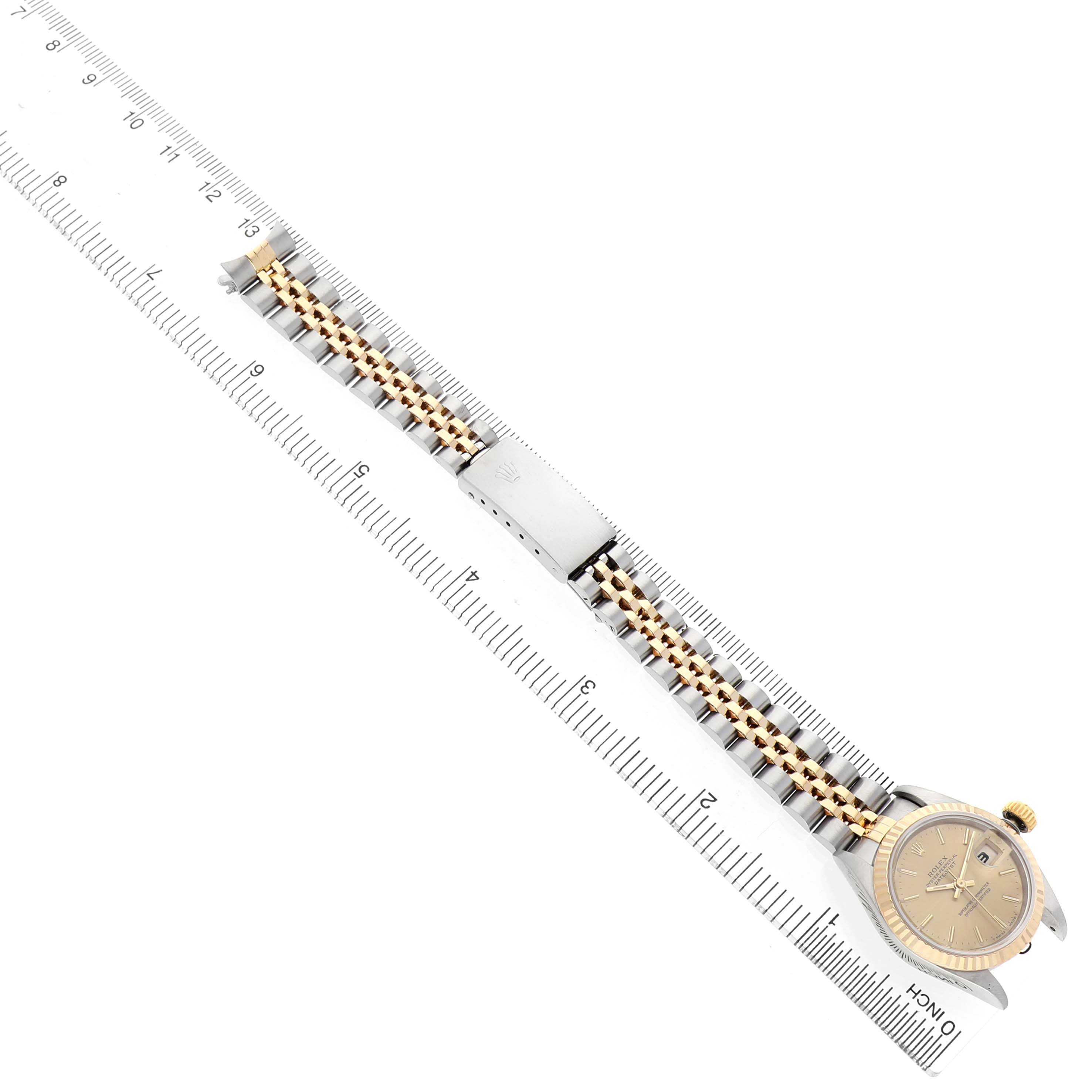 The Rolex Datejust 69173 Women's Steel and Gold (two tone) Champagne Dial watch is shown at an angle displaying the full bracelet, clasp, and face, aligned with a ruler.