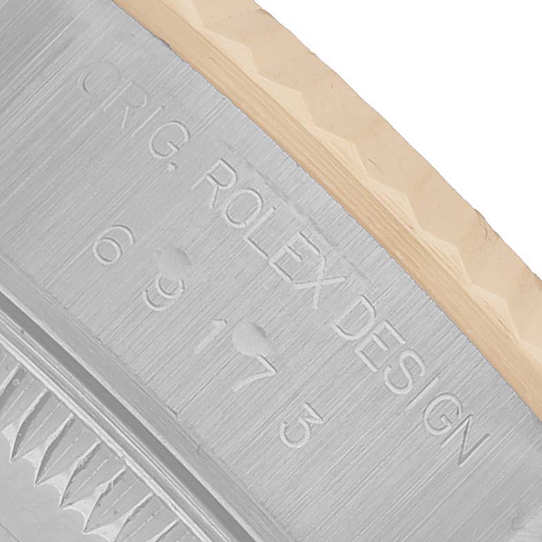 The image shows a close-up of the engraved side of the case of a Rolex Datejust 69173 Women's Steel and Gold (two tone) White Dial, highlighting the design and serial details.