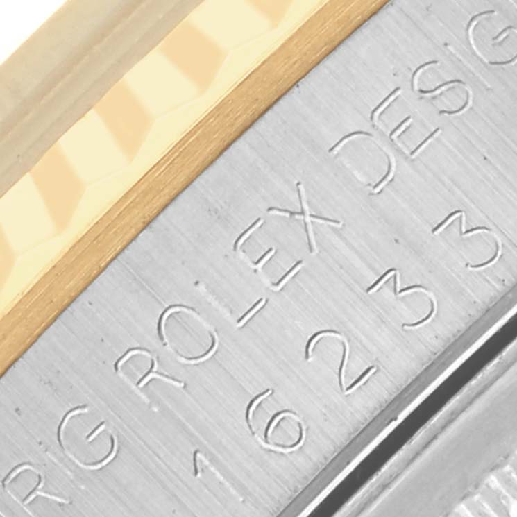 The image shows a close-up of the bezel and engraved side of a Rolex Datejust 16233 Men's Steel and Gold (two tone) Blue Dial 16233 Men's Steel and Gold (two tone) Blue Dial watch, highlighting the brushed metal texture.