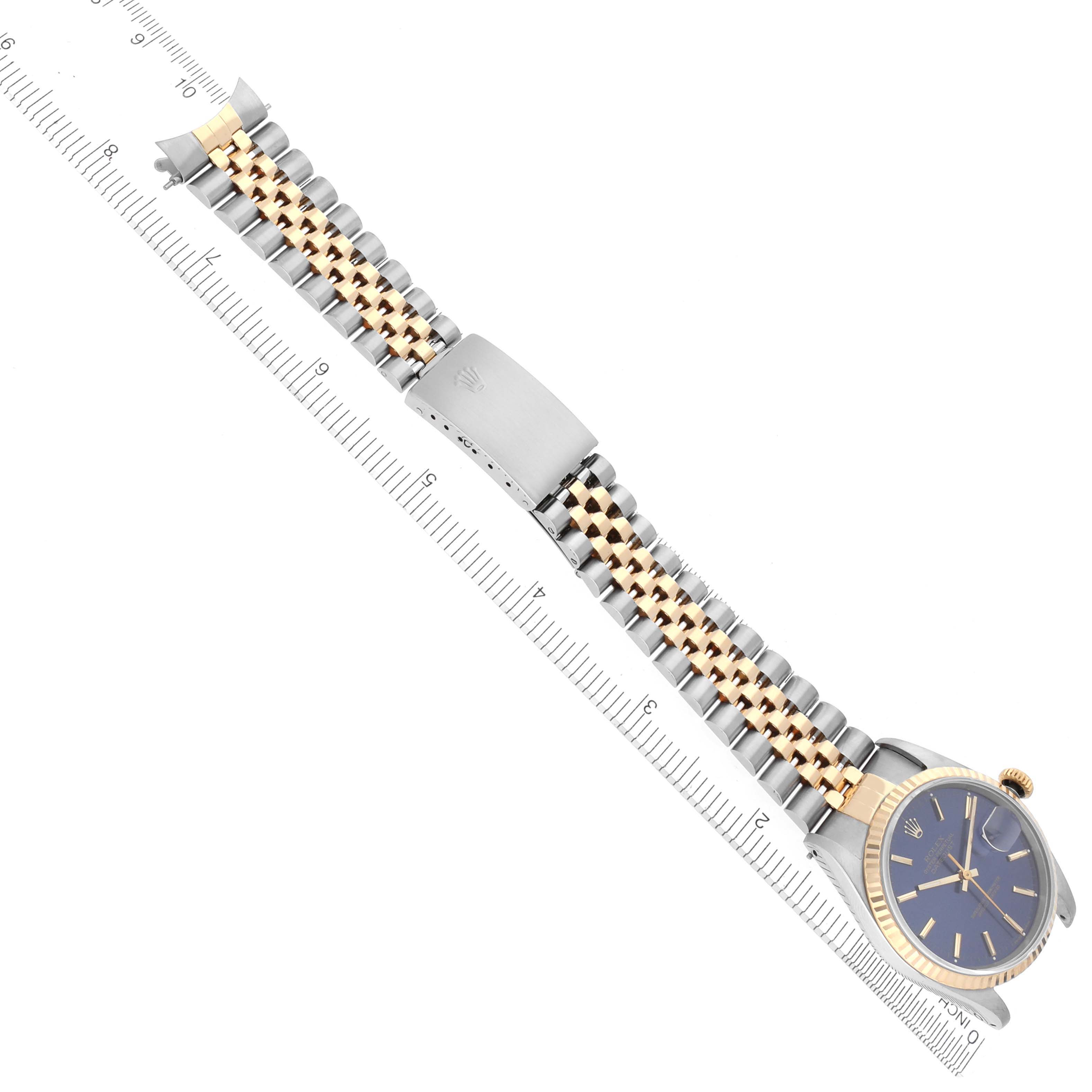 The image shows a Rolex Datejust 16233 Men's Steel and Gold (two tone) Blue Dial 16233 Men's Steel and Gold (two tone) Blue Dial watch at an overhead angle, highlighting its bracelet and case next to a ruler.