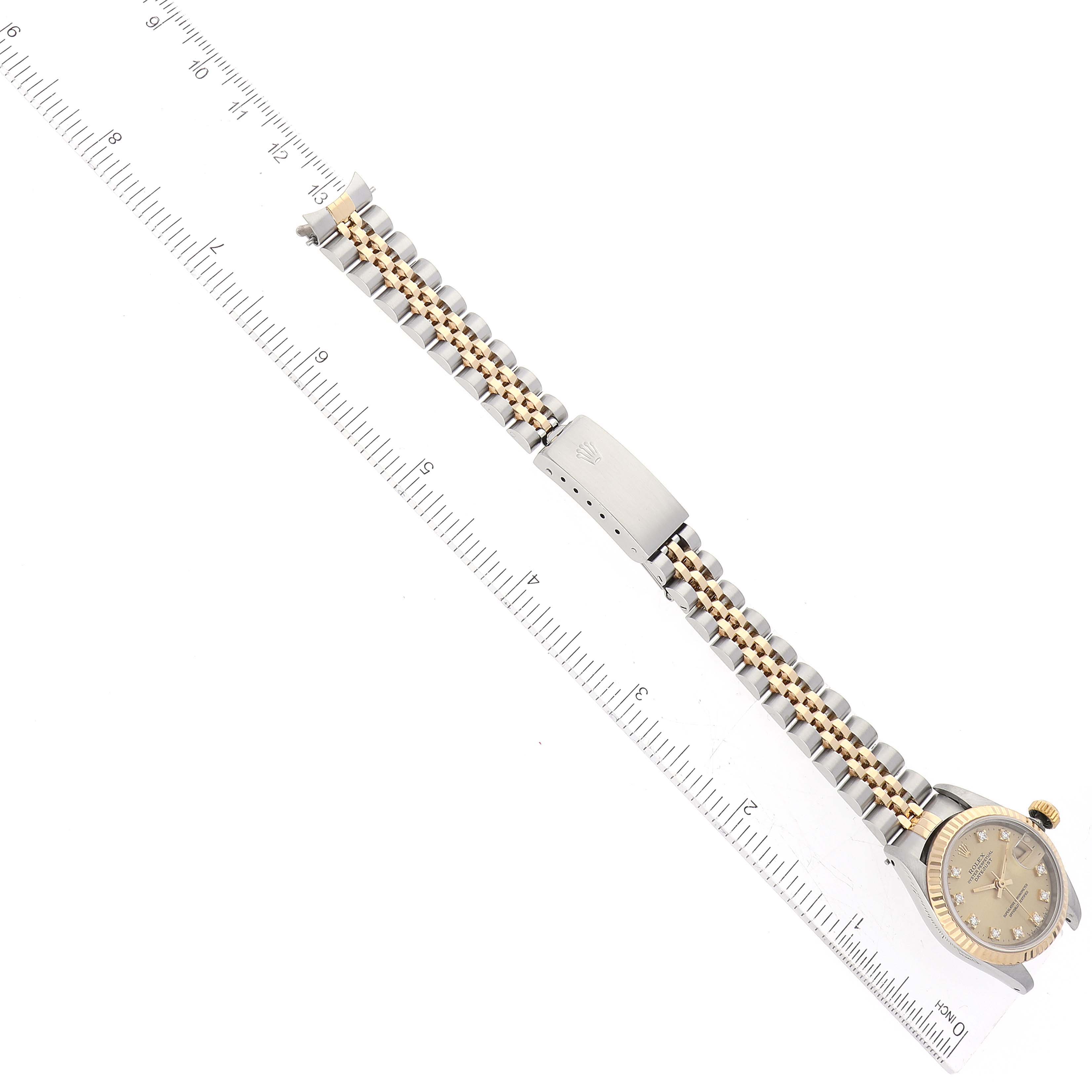 The image shows a Rolex Datejust 69173 Women's Steel and Gold (two tone) Champagne Dial 69173 Women's Steel and Gold (two tone) Champagne Dial watch laid flat, highlighting the face, bracelet, and clasp, with a ruler for scale.