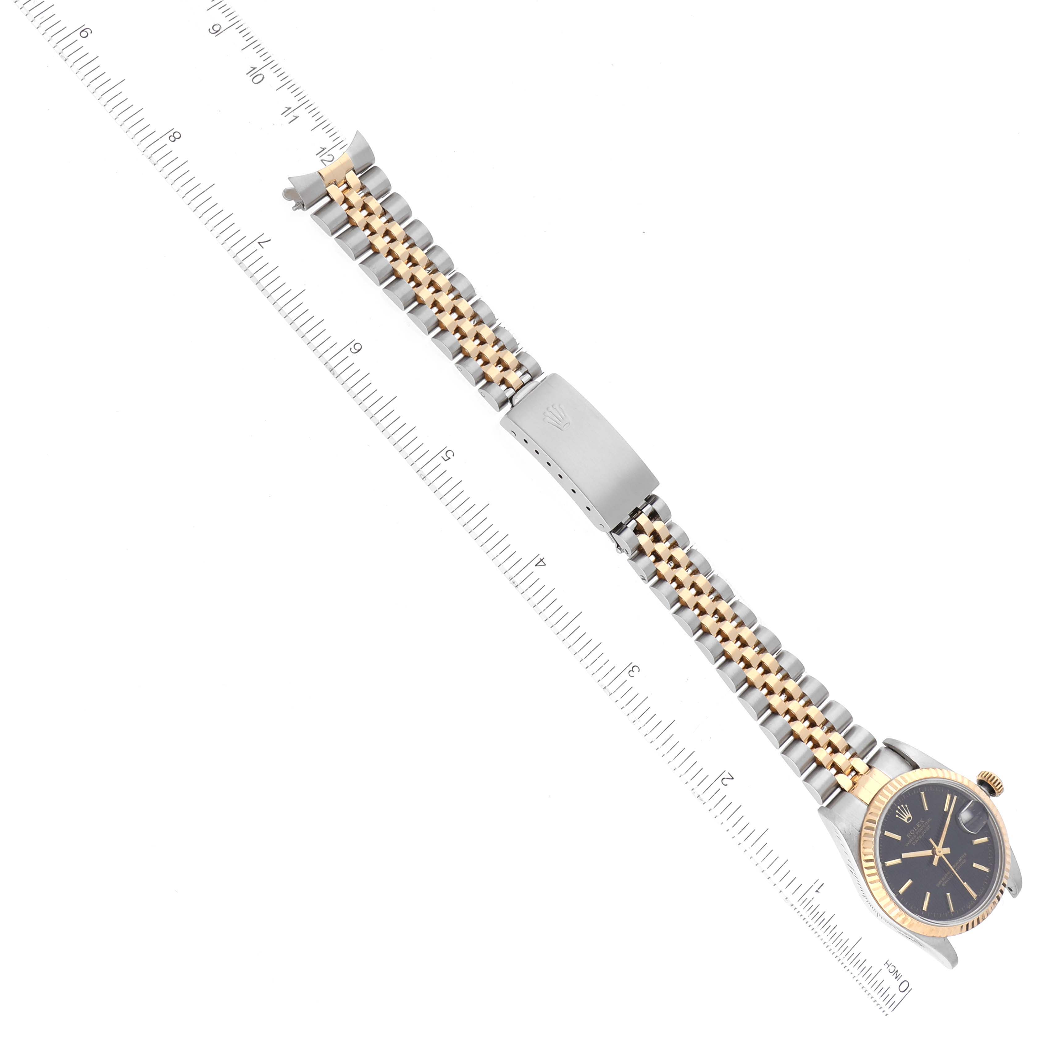 The image shows an overhead view of a Rolex Mid-Size 68273 Women's Steel and Gold (two tone) Black Dial 68273 Women's Steel and Gold (two tone) Black Dial watch, displaying the face, crown, and two-toned bracelet with a ruler for scale.