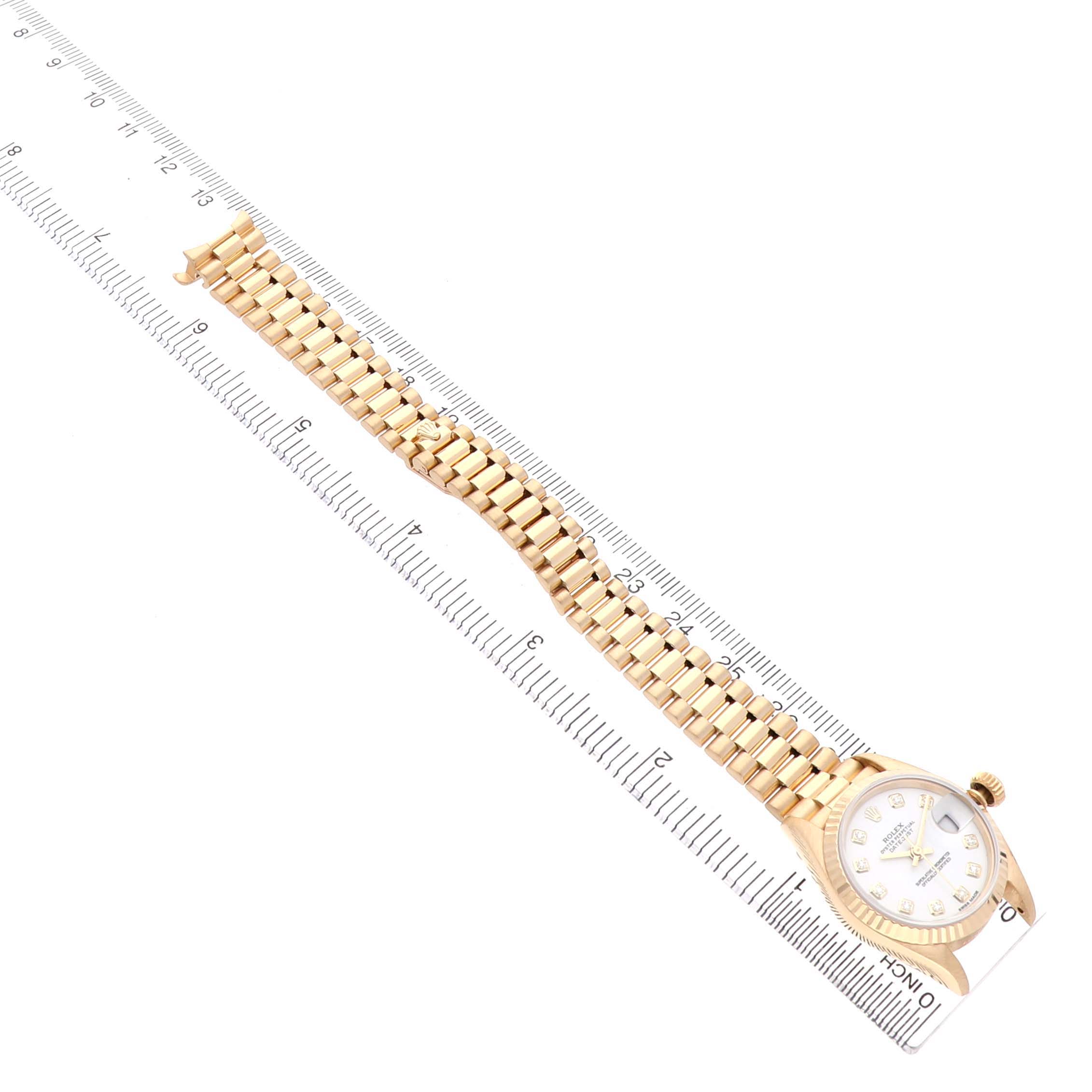 The Rolex President 69178 Women's Yellow Gold White Dial watch is shown from an overhead angle, displaying the bracelet and face alongside a ruler for scale.