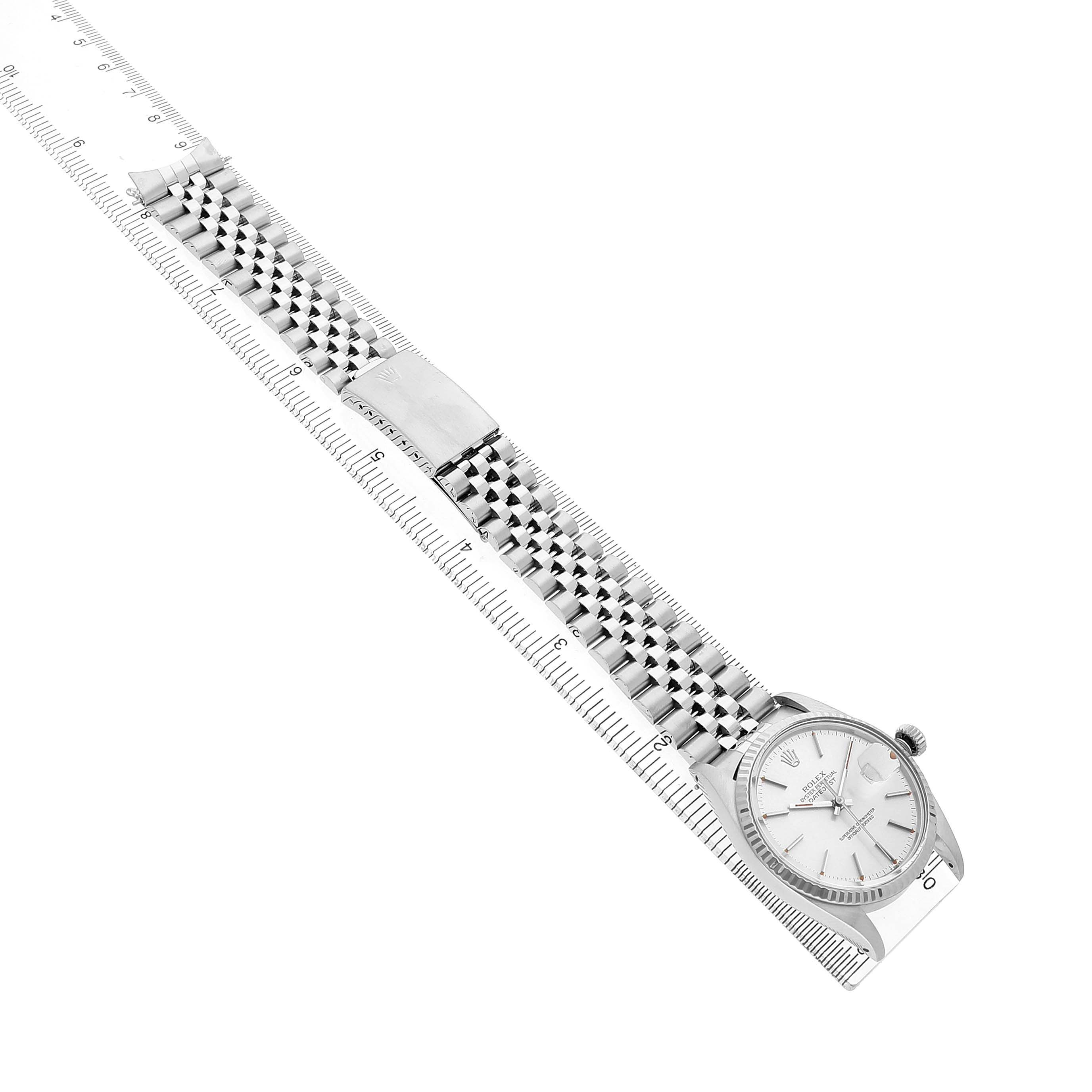 The Rolex Datejust 16014 Men's Stainless Steel Silver Dial watch is shown from a top view, highlighting the face and full bracelet alongside a ruler for scale.