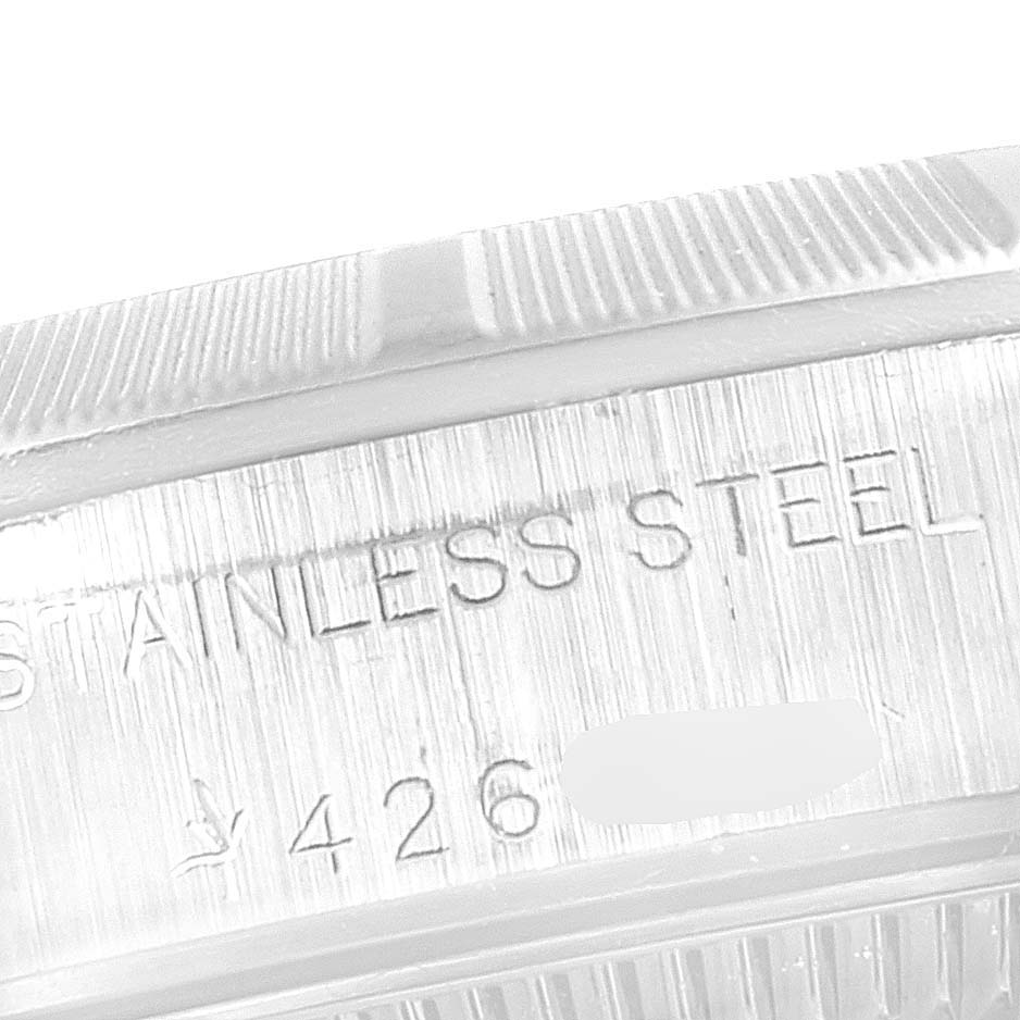 This close-up image shows the side of the bezel and caseback of a Rolex Oyster Perpetual 76030 Women's Stainless Steel Silver Dial 76030 Women's Stainless Steel Silver Dial watch, marked "STAINLESS STEEL."