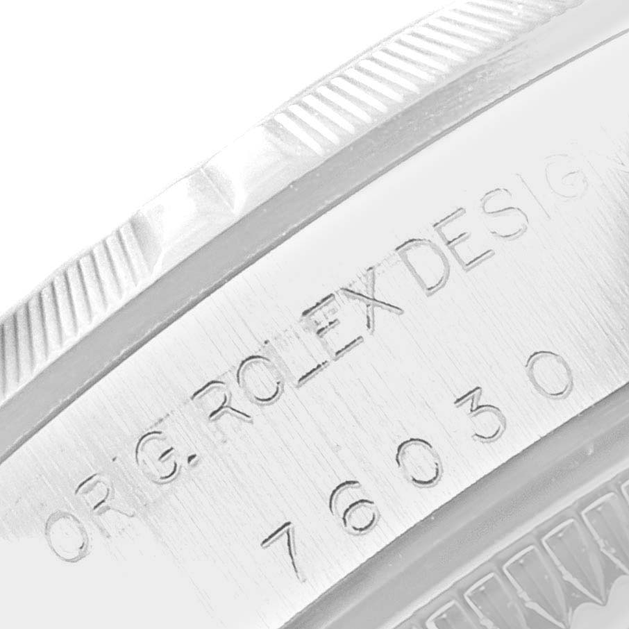 The image shows a close-up of the Oyster Perpetual by Rolex, focusing on the engraved model number and part of the fluted bezel.