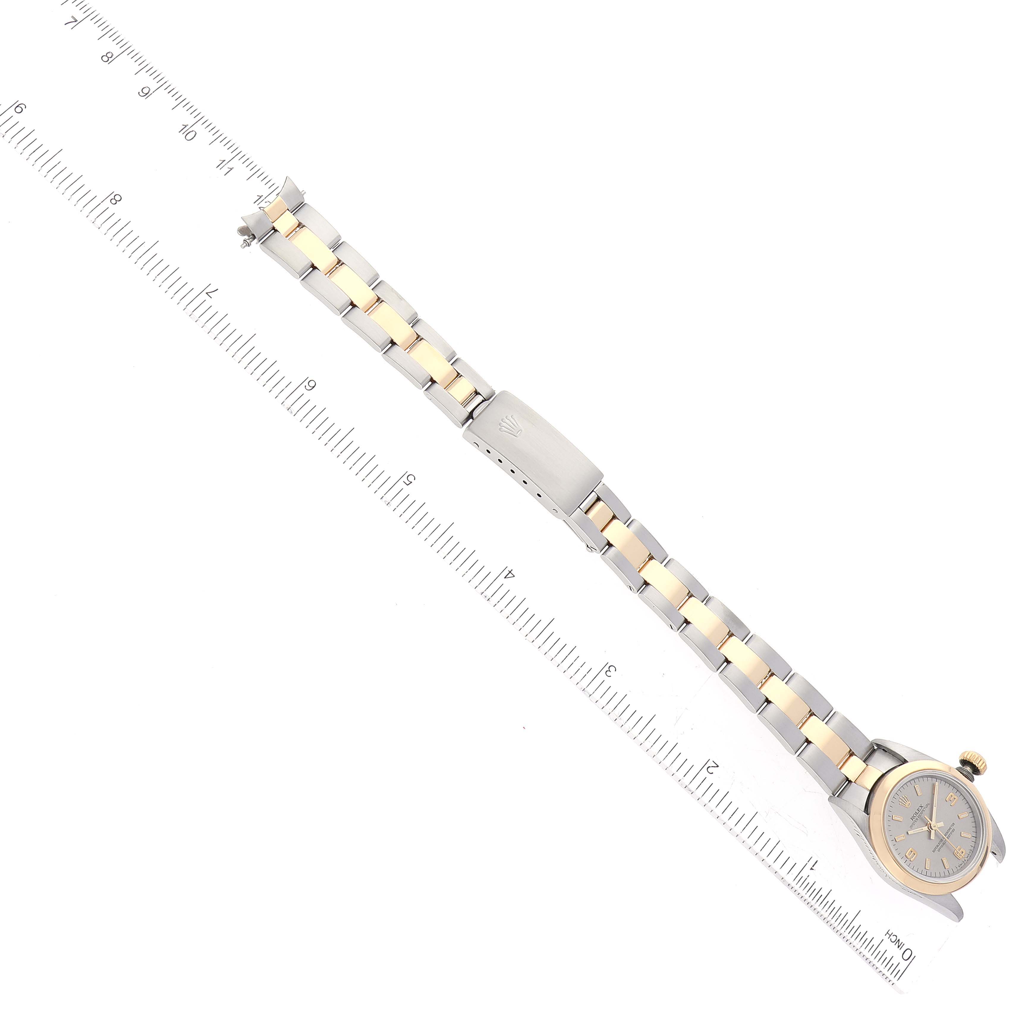 This image shows a top-down view of a Rolex Oyster Perpetual 67183 Women's Steel and Gold (two tone) Grey Dial 67183 Women's Steel and Gold (two tone) Grey Dial watch, including the face, bracelet, and clasp, against a ruler for scale.