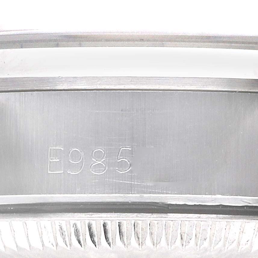The image shows the inner casing of a Rolex Oyster Perpetual 67180 Women's Stainless Steel White Dial 67180 Women's Stainless Steel White Dial with engraved serial number "E985."