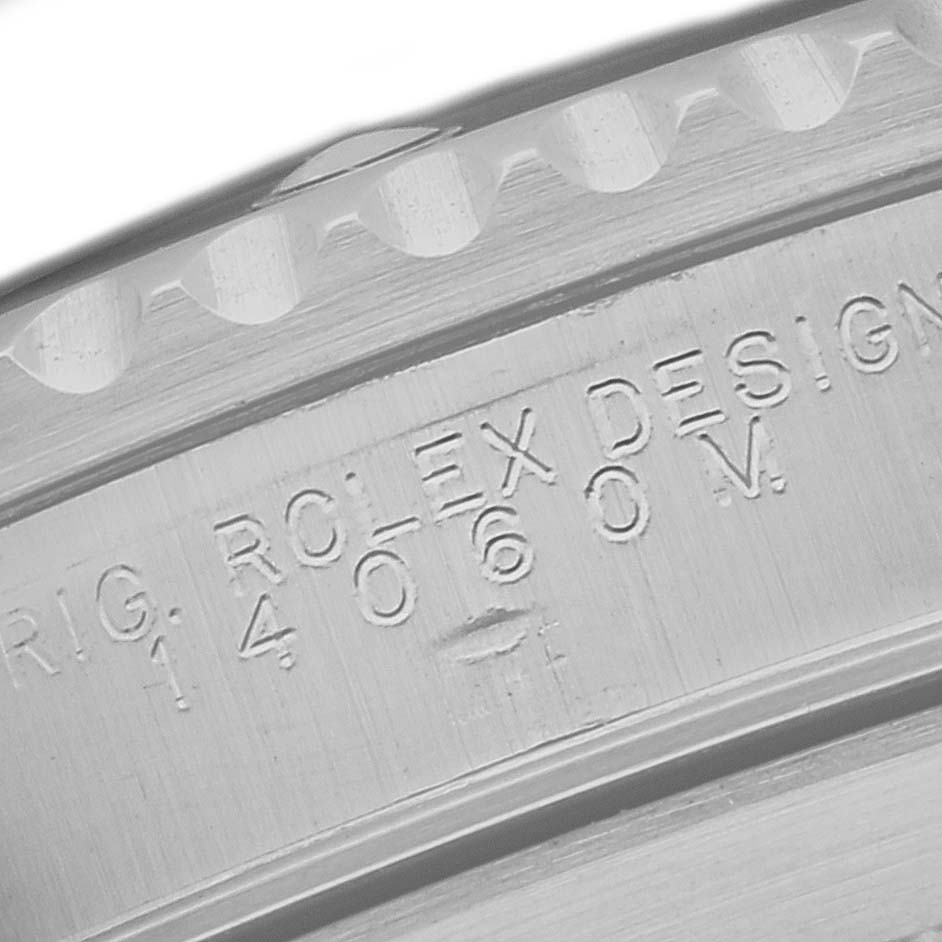 The image shows a close-up of the engraved serial number on the side of a Rolex Submariner 14060 Men
s Stainless Steel Black Dial 14060 Men
s Stainless Steel Black Dial watch case.