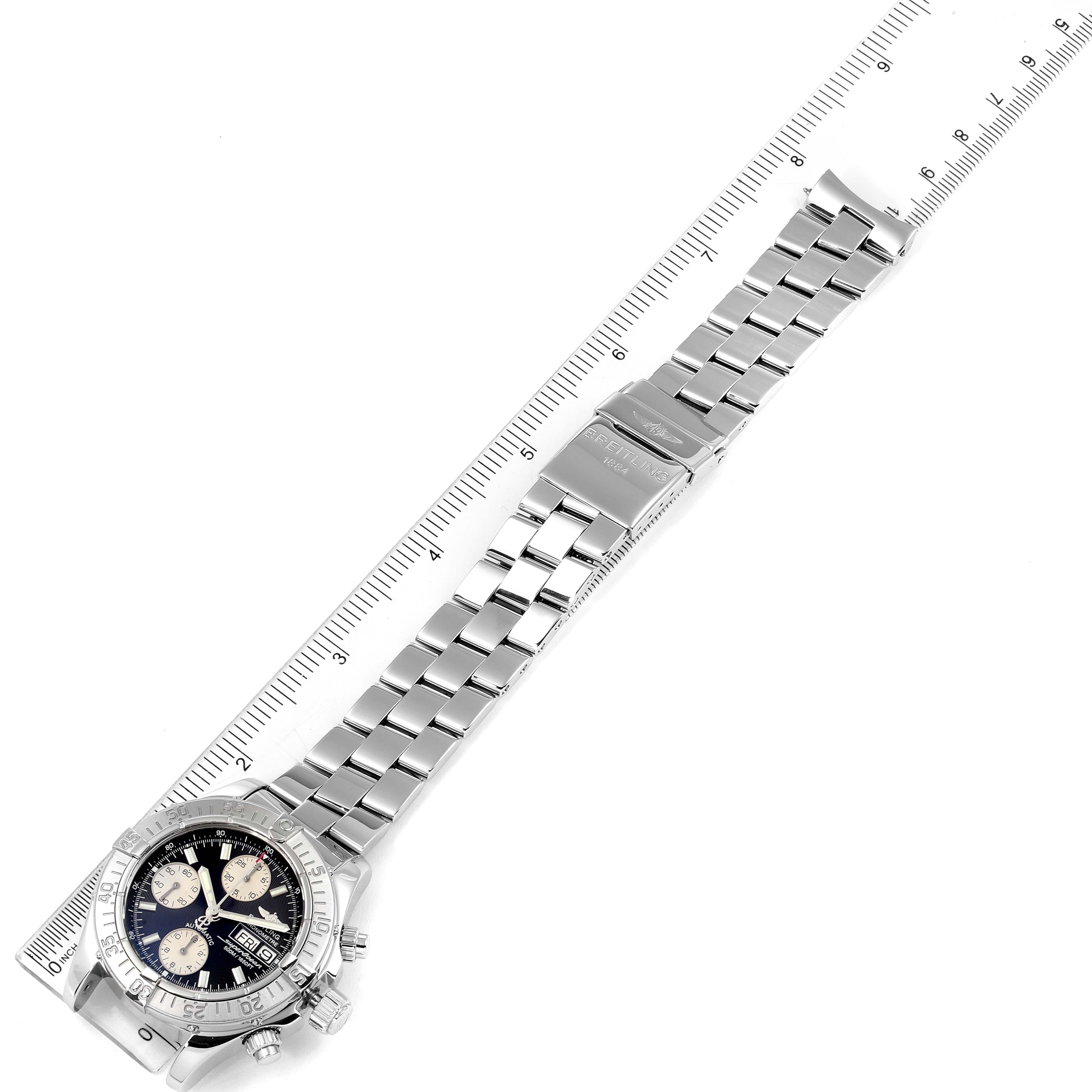 The image shows a top-down view of a Breitling Superocean A13340 Men's Stainless Steel Black Dial A13340 Men's Stainless Steel Black Dial watch along its metal bracelet placed alongside a ruler.