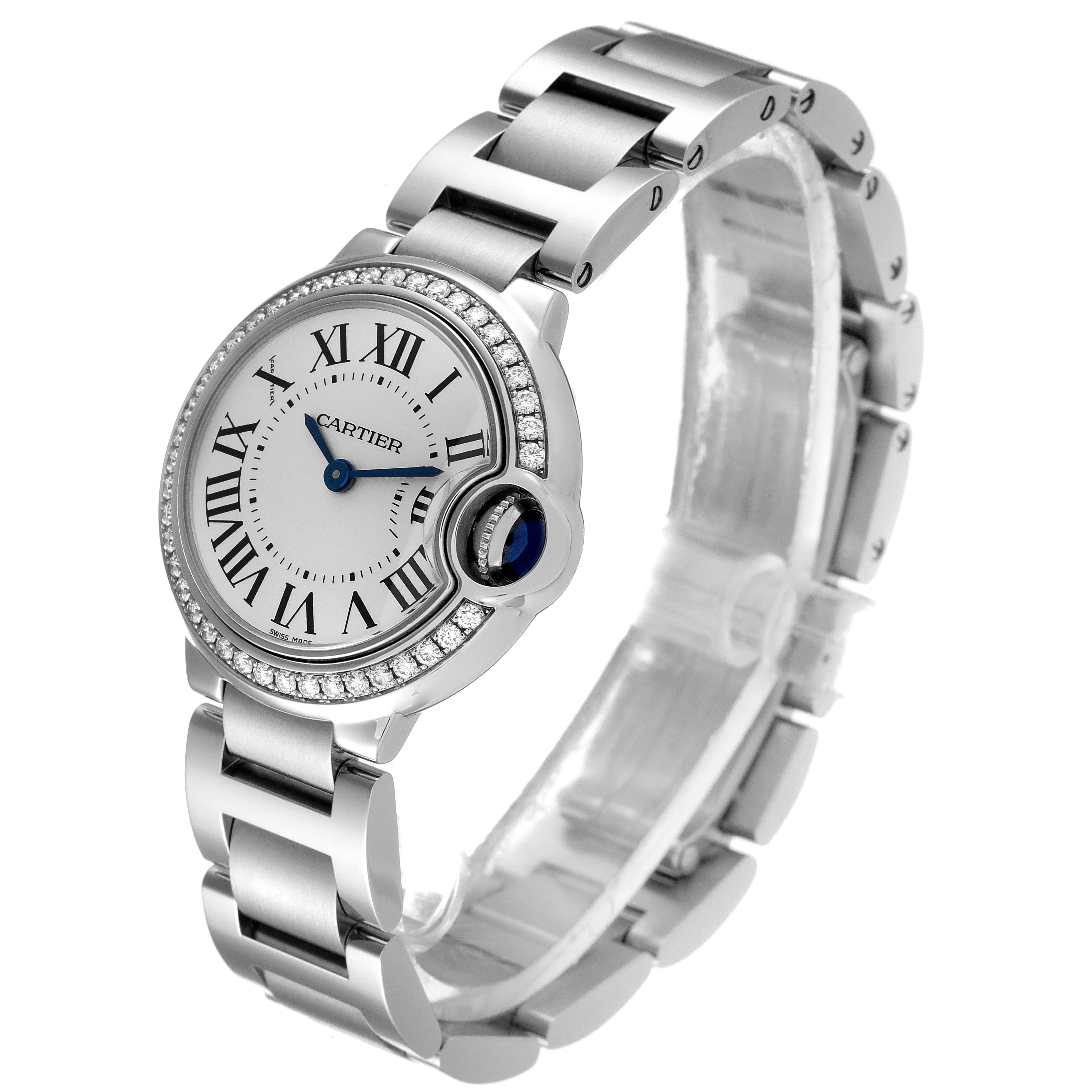 The image shows a Cartier Ballon Bleu W4BB0015 Women
s Stainless Steel Silver Dial W4BB0015 Women
s Stainless Steel Silver Dial watch at an angle highlighting its round face, metal bracelet, and blue gemstone crown.
