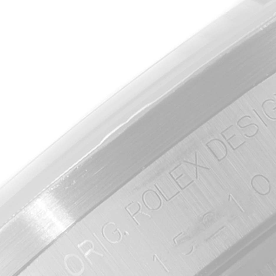 This close-up image shows the side view of the metal casing of a Rolex Date 15210 Men's Stainless Steel Black Dial 15210 Men's Stainless Steel Black Dial model watch with engraving.