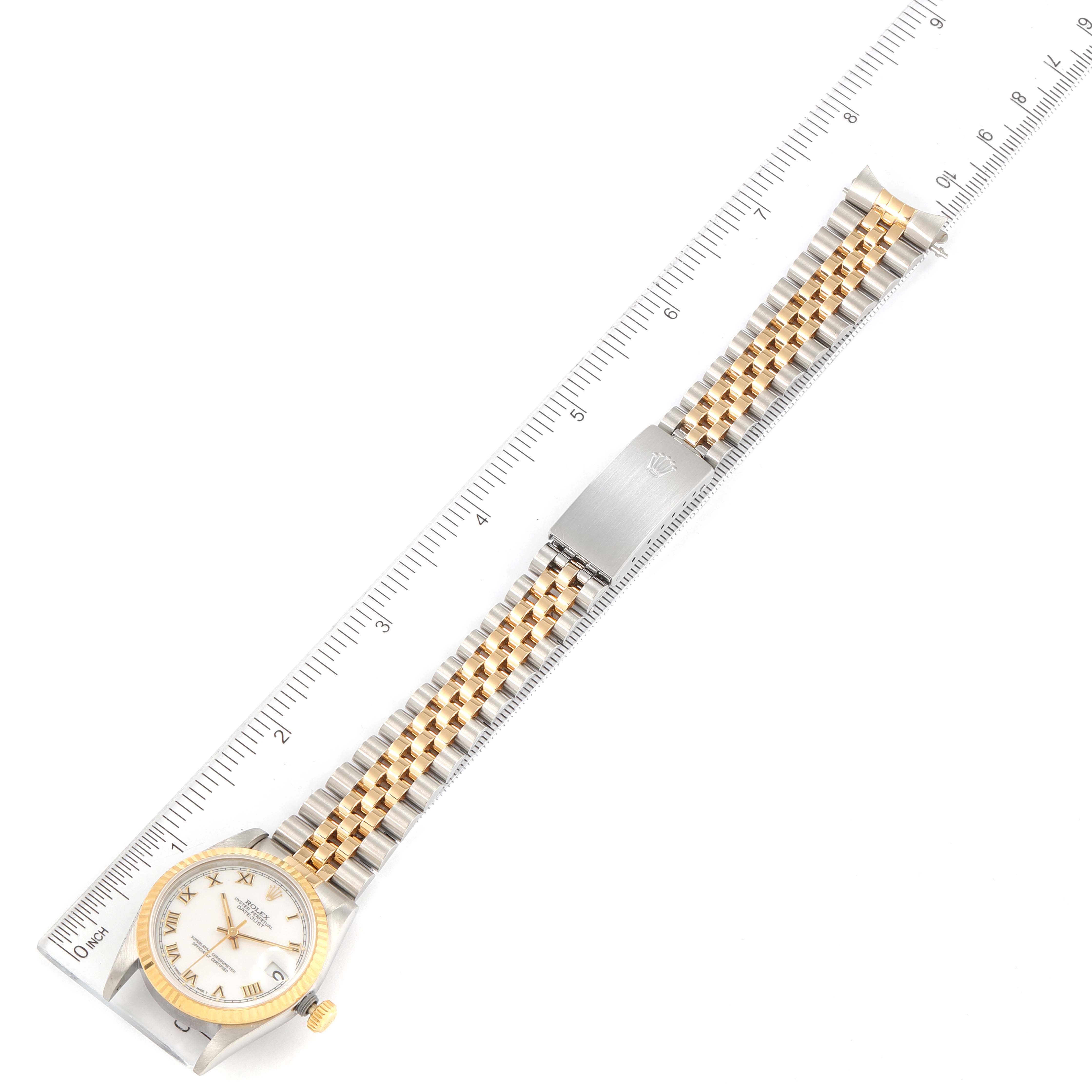 The Rolex Mid-Size 68273 Women
s Steel and Gold (two tone) White Dial 68273 Women
s Steel and Gold (two tone) White Dial watch is shown from a top-down angle, displaying its face, bezel, and bracelet alongside a ruler for scale.