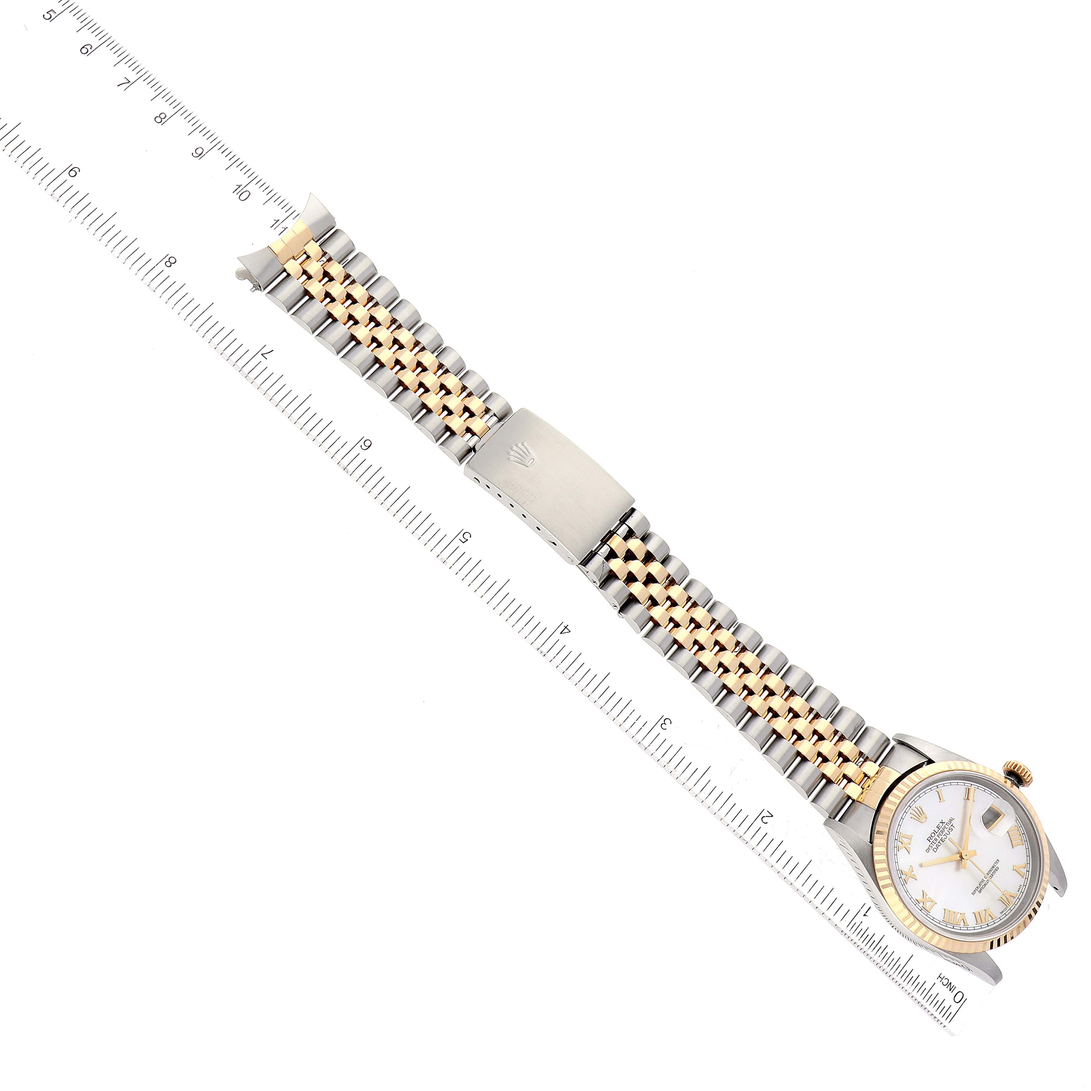 The Rolex Datejust 16233NR Men's Steel and Gold (two tone) Mother of Pearl Dial 16233NR Men's Steel and Gold (two tone) Mother of Pearl Dial watch is shown from an overhead angle, displaying the face, band, clasp, and a ruler for scale.