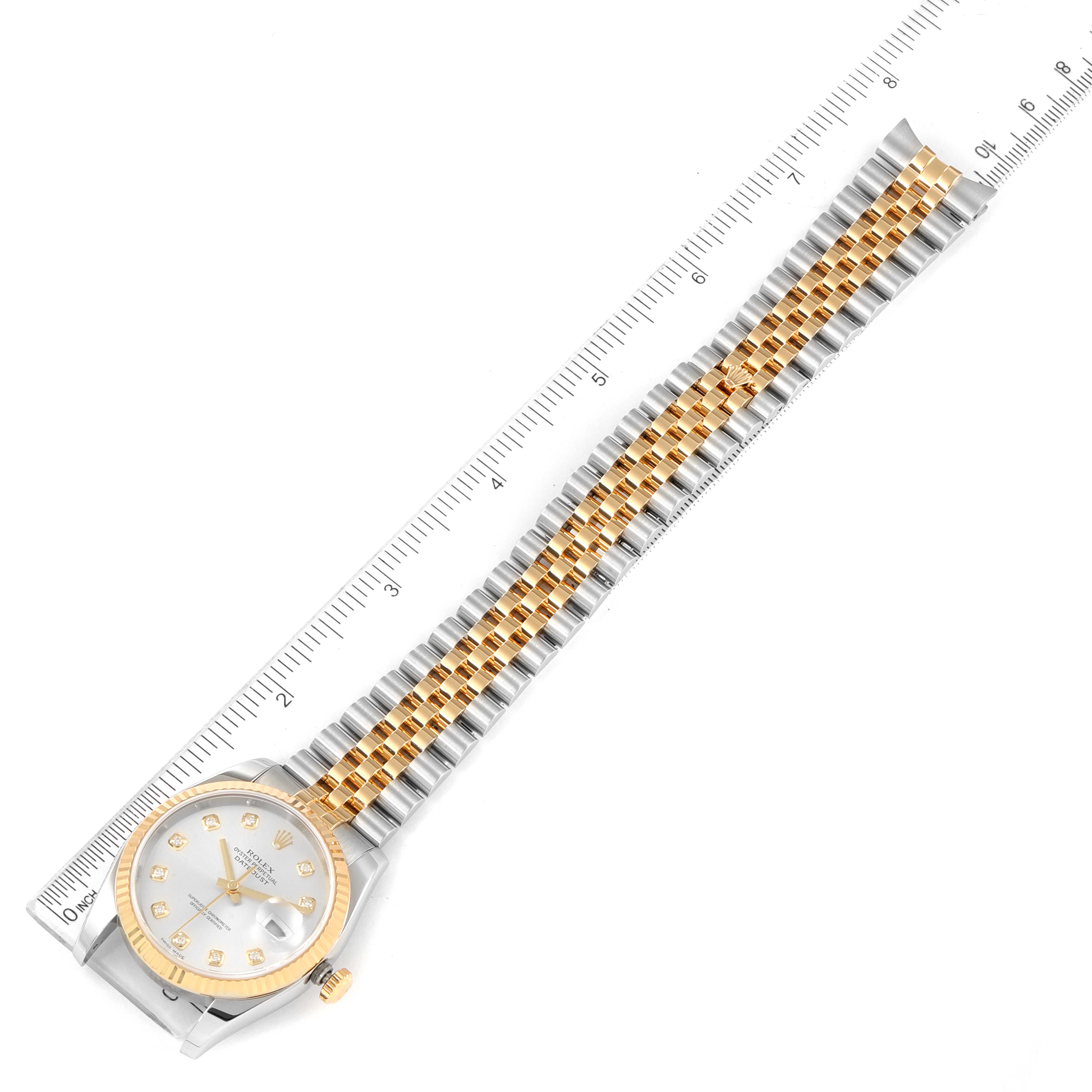 The Rolex Datejust 116233 Men's Steel and Gold (two tone) Silver Dial 116233 Men's Steel and Gold (two tone) Silver Dial watch is shown from a top-down angle with a measuring ruler alongside it.