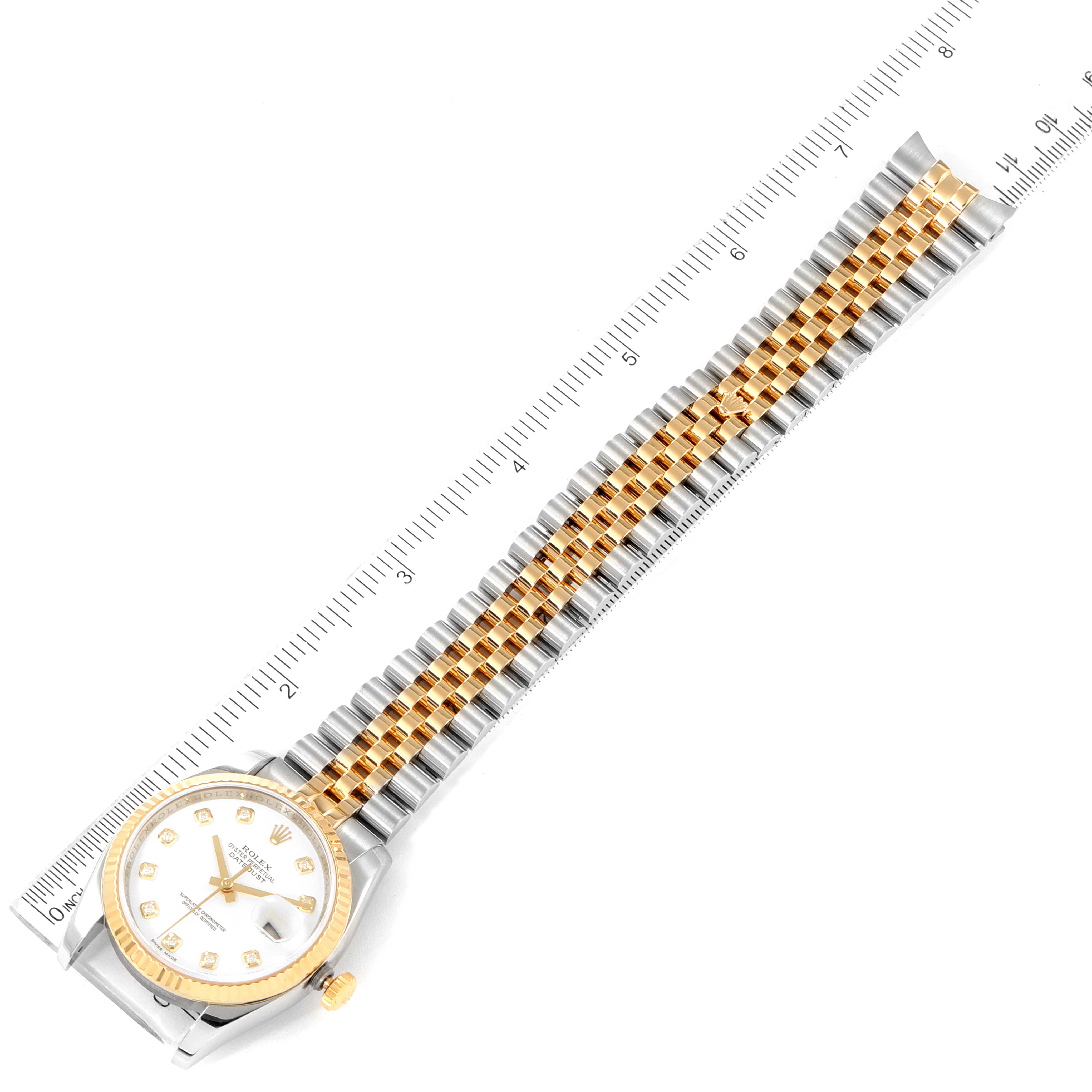 The Rolex Datejust 116233 Men's Steel and Gold (two tone) White Dial 116233 Men's Steel and Gold (two tone) White Dial watch is shown from a top-down angle, with its face and full bracelet visible, alongside a ruler for scale.