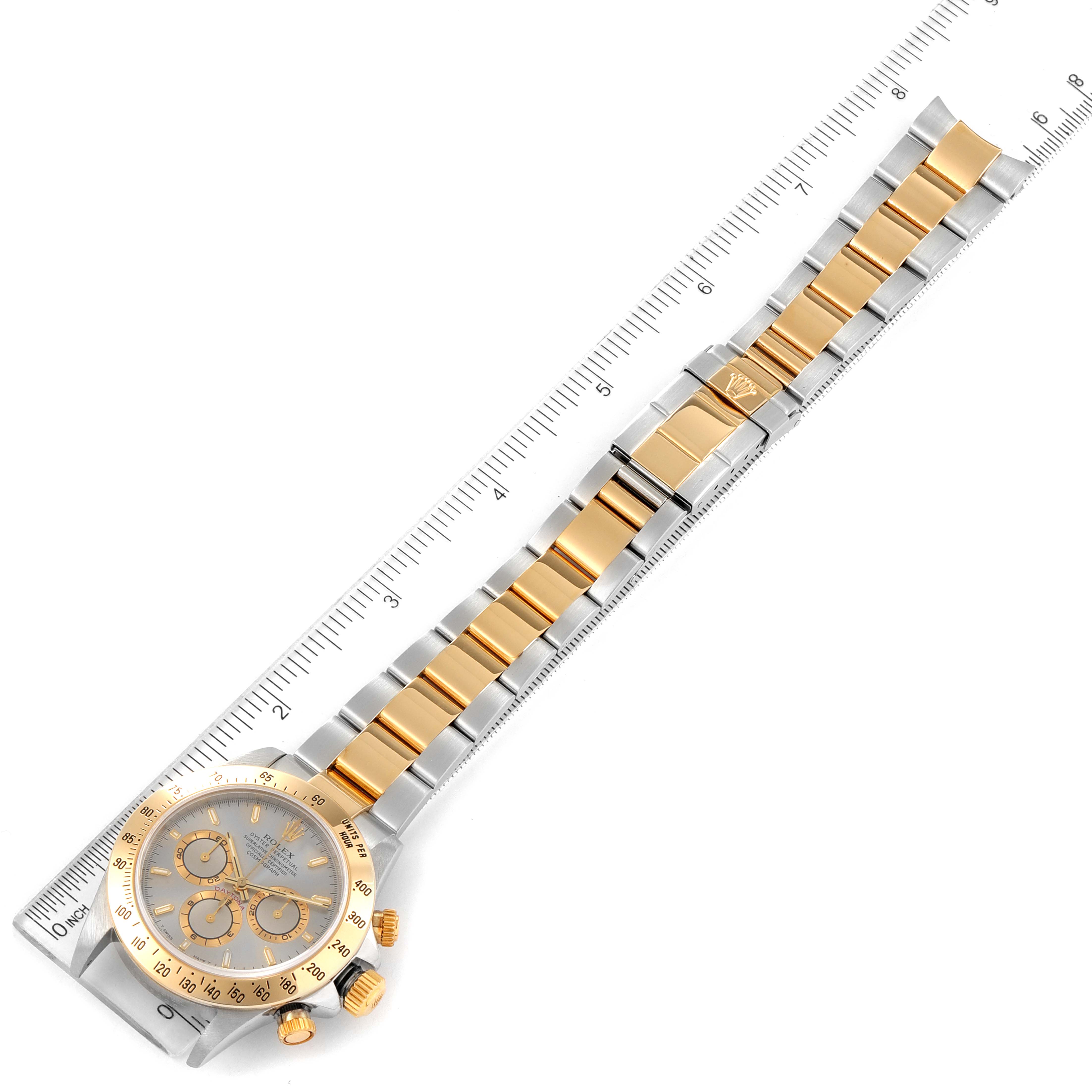 The image shows a Rolex Daytona 16523 Men
s Steel and Gold (two tone) Grey Dial 16523 Men
s Steel and Gold (two tone) Grey Dial watch laid flat with a ruler measuring the length of its gold and silver bracelet.