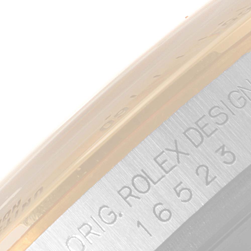 The image shows a close-up of the side bezel and casing of a Rolex Daytona 16523 Men
s Steel and Gold (two tone) Grey Dial 16523 Men
s Steel and Gold (two tone) Grey Dial watch, highlighting the engraving.