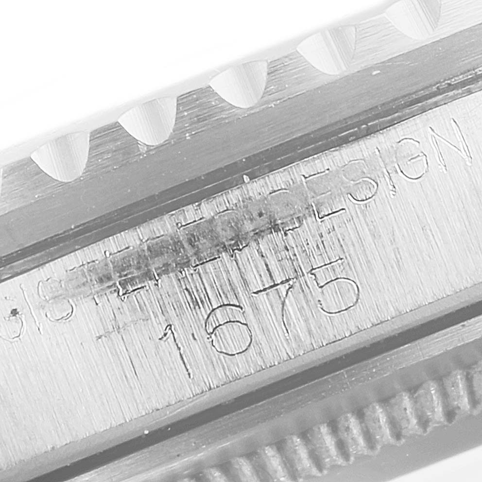 This close-up image shows the engraved model number and part of the bezel of a Rolex Vintage Collection 1675 Men's Stainless Steel Black Dial 1675 Men's Stainless Steel Black Dial watch.