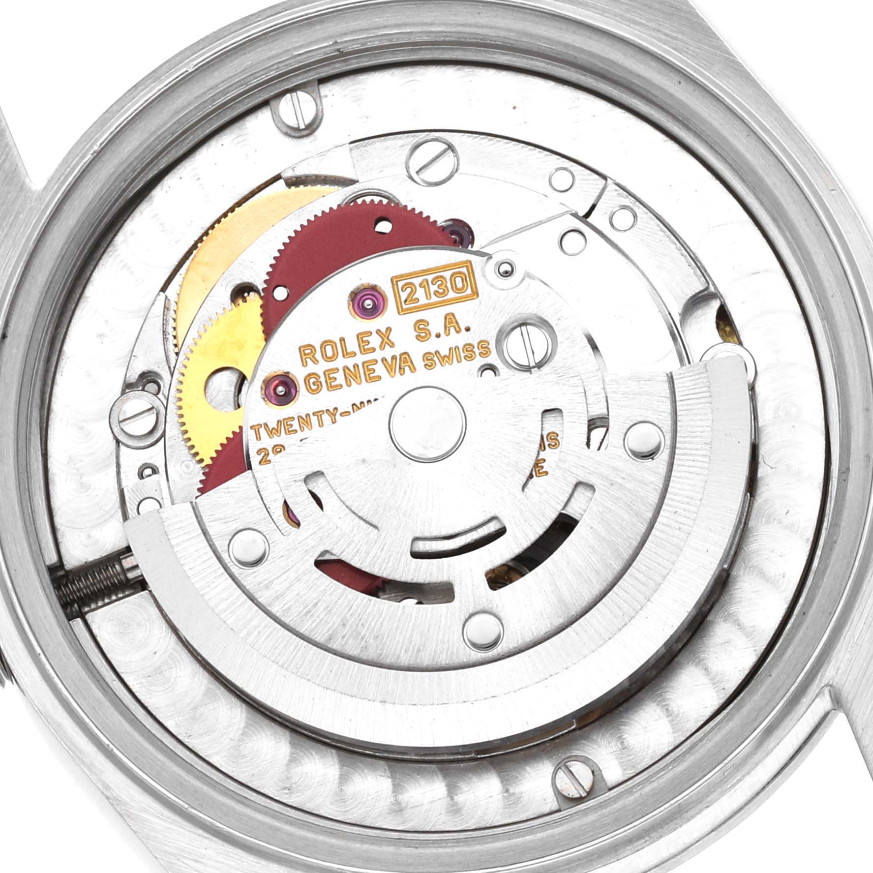 A close-up view of the movement mechanism inside a Mid-Size Rolex watch, showing gears and the engraved brand details.