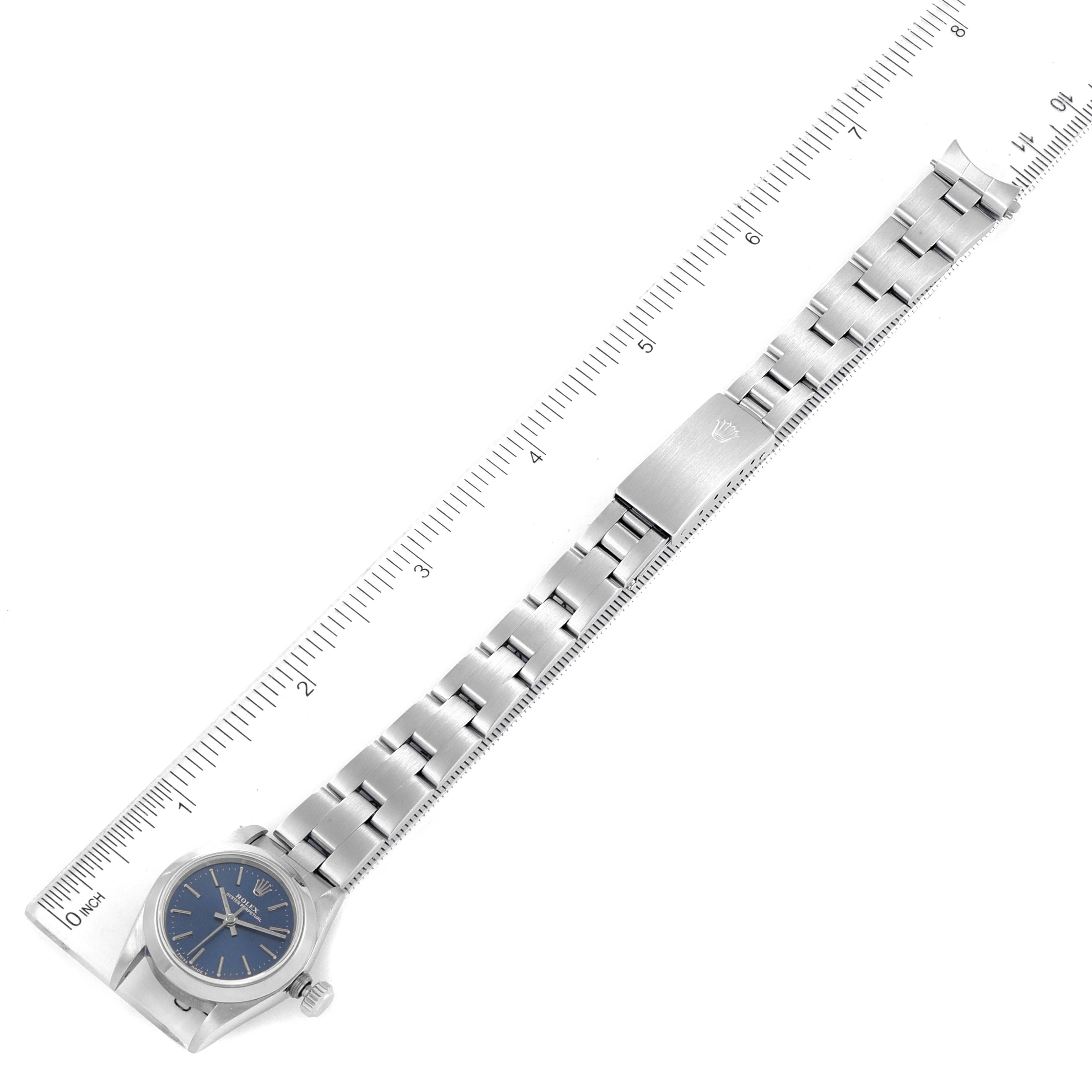 This image shows a side view of a Rolex Oyster Perpetual 67180 Women
s Stainless Steel Blue Dial 67180 Women
s Stainless Steel Blue Dial watch, including its blue dial, bezel, and metal bracelet with a ruler for scale.