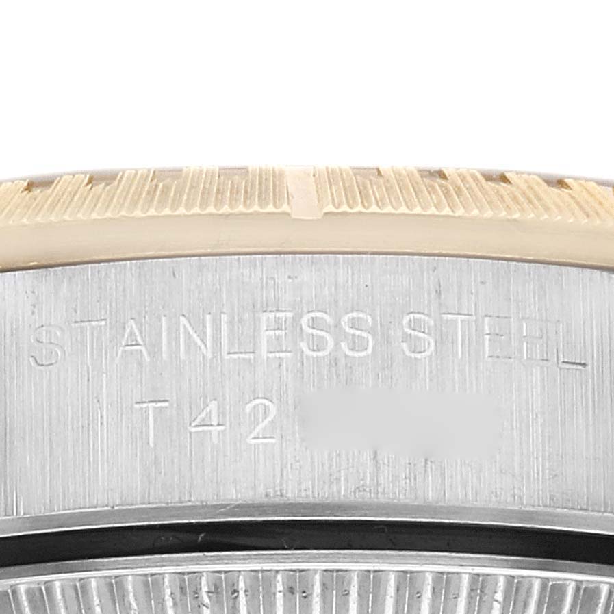 The image shows a close-up of the side of a Rolex Oyster Perpetual 67243 Women's Steel and Gold (two tone) Champagne Dial 67243 Women's Steel and Gold (two tone) Champagne Dial watch, highlighting its stainless steel bezel and engraved text.