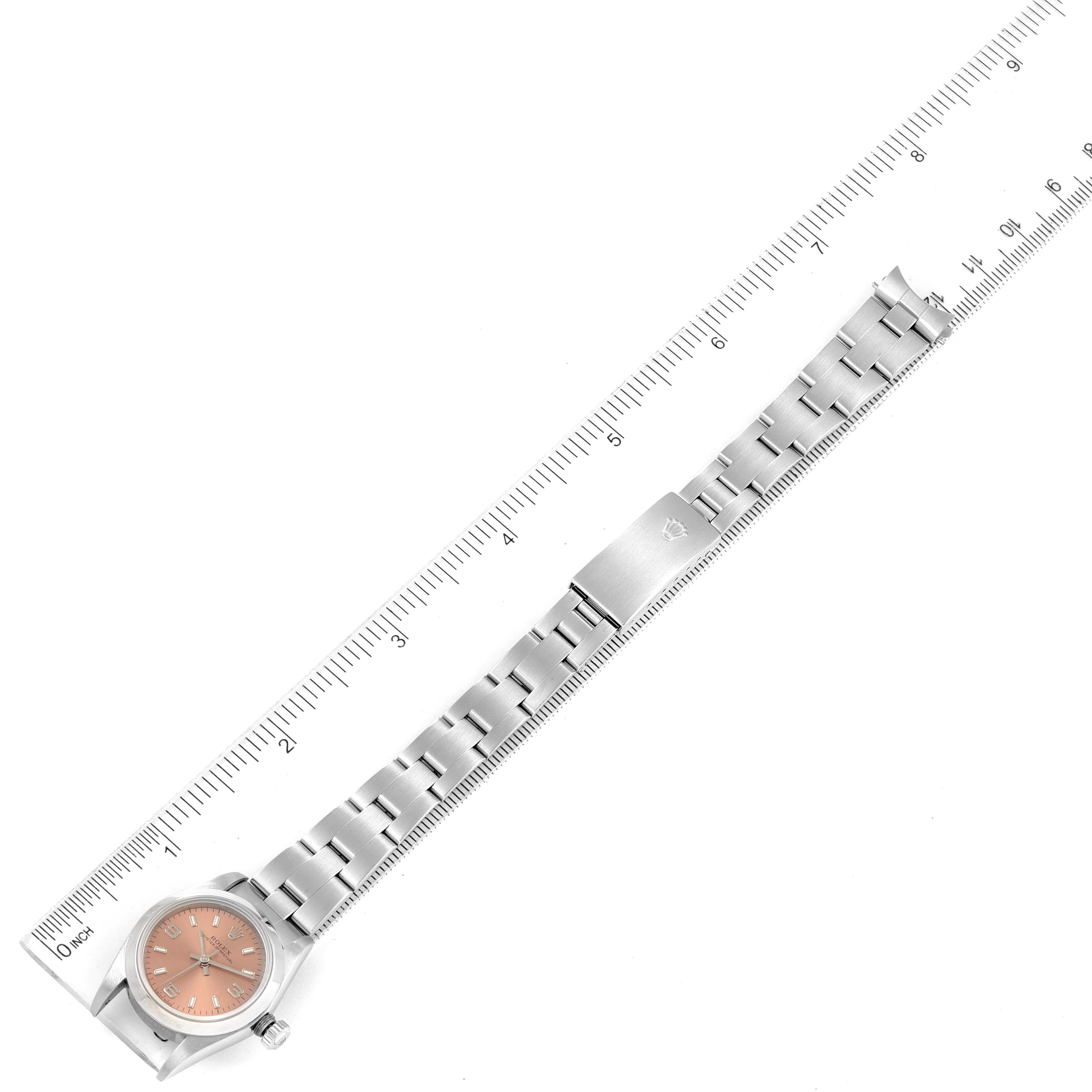 The image shows a Rolex Oyster Perpetual 76080 Women
s Stainless Steel Pink Dial 76080 Women
s Stainless Steel Pink Dial watch horizontally with its stainless steel strap extended and aligned with a ruler.
