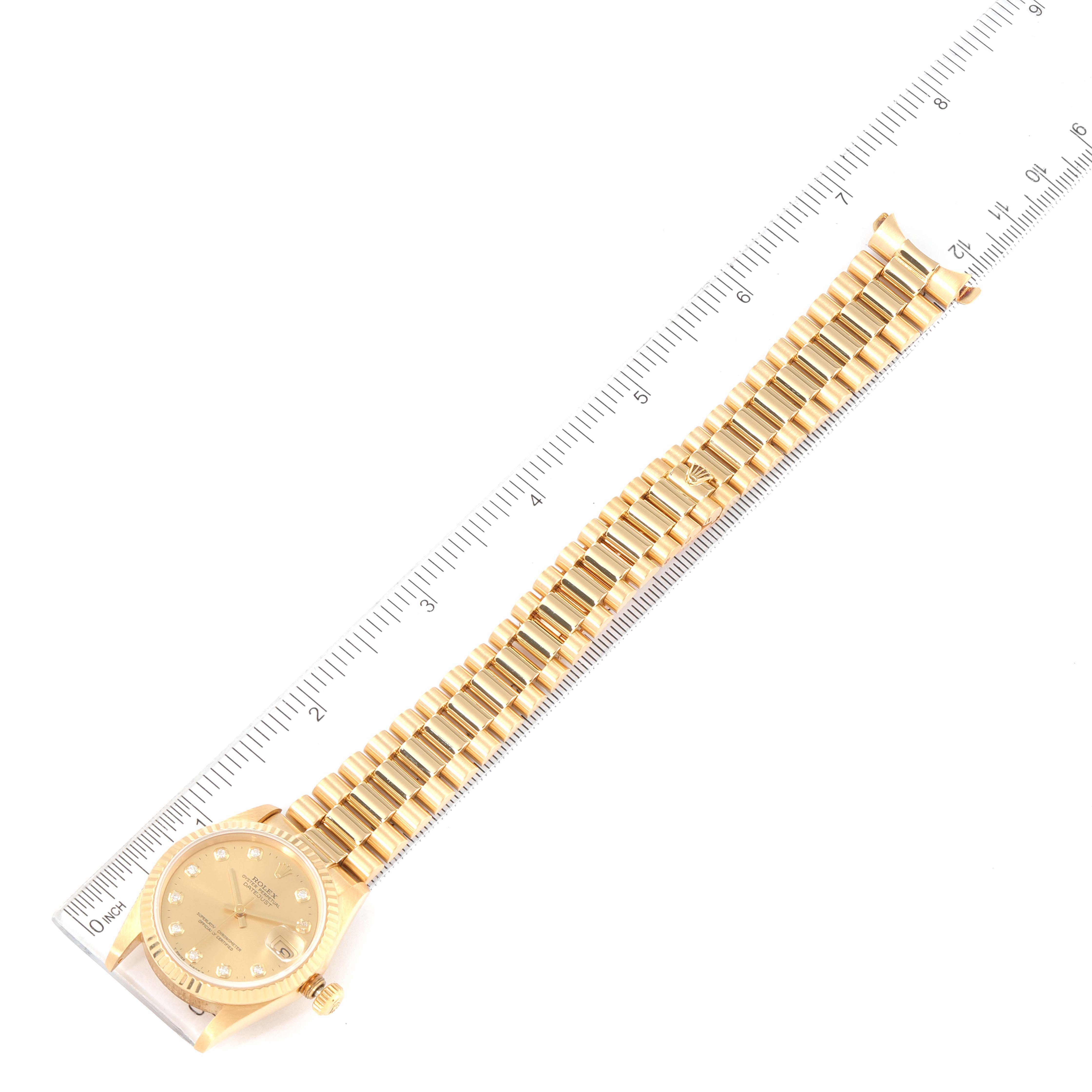 The Rolex President 68278 Women's Yellow Gold Champagne Dial 68278 Women's Yellow Gold Champagne Dial model watch is shown at an overhead angle, displaying its entire gold band and face, with a ruler for scale.