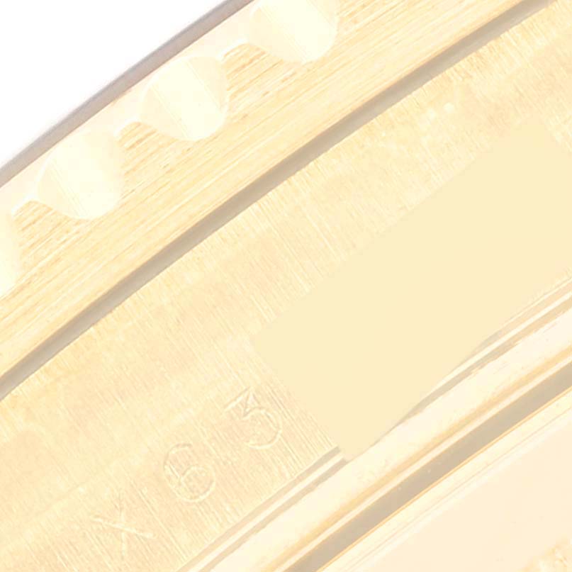 This close-up image shows the edge of the Rolex Submariner 16618 Men's Yellow Gold Blue Dial 16618 Men's Yellow Gold Blue Dial watch case and part of its engraved serial number.