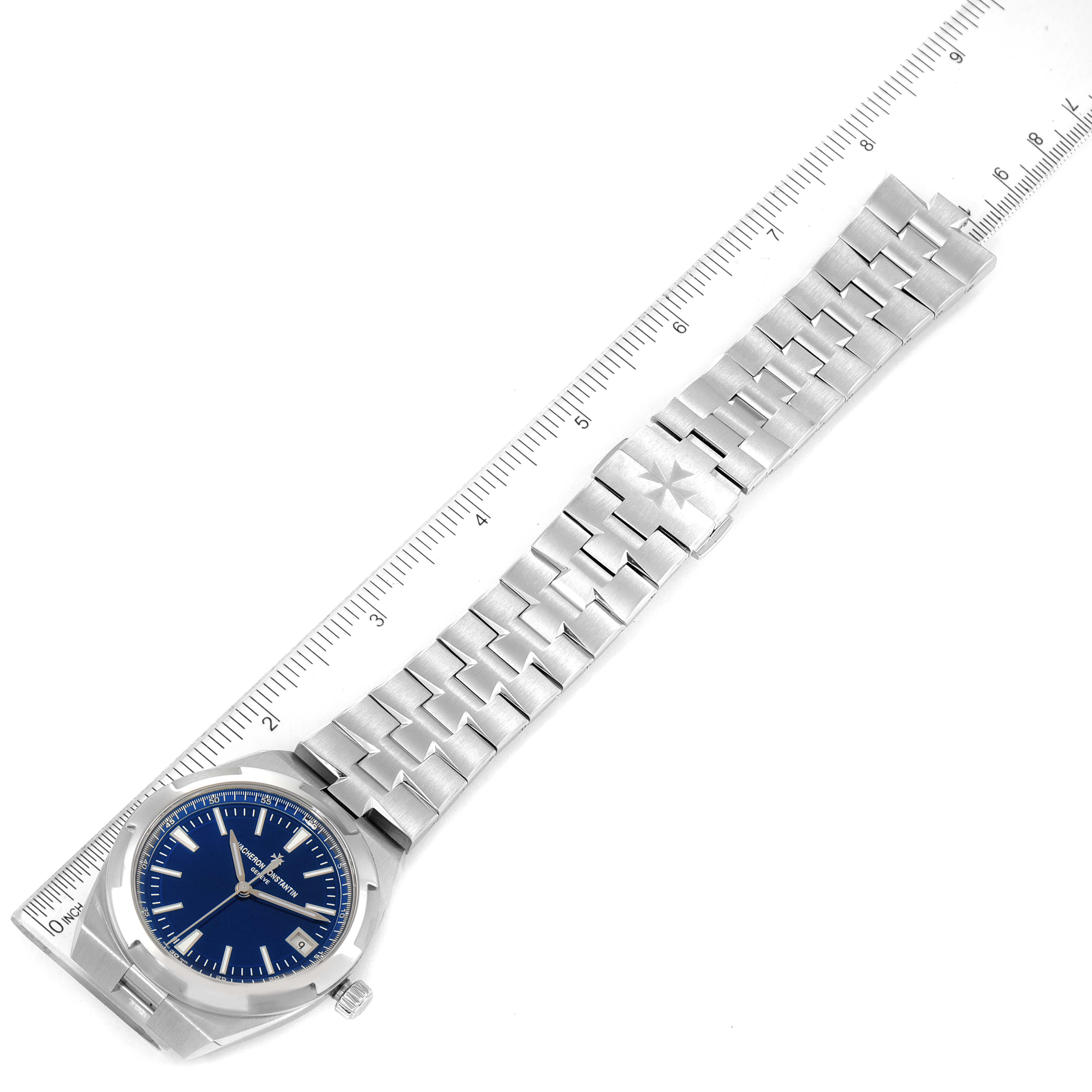 The image shows a Vacheron Constantin Overseas 4500V/110A-B128 Men's Stainless Steel Blue Dial 4500V/110A-B128 Men's Stainless Steel Blue Dial model watch laid flat, displaying its blue dial, stainless steel case, and bracelet with a ruler beside it.
