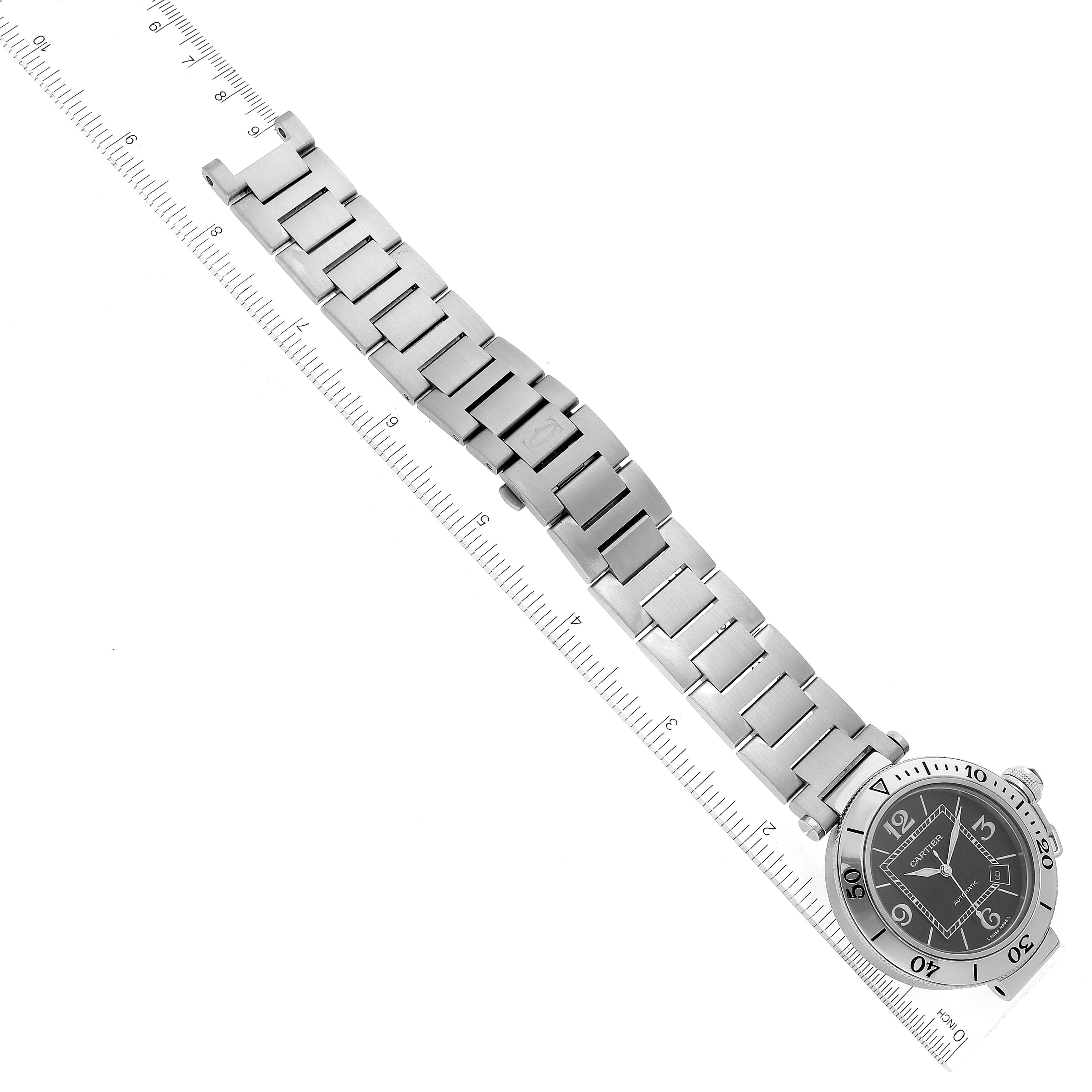 The image shows a Pasha model watch by Cartier, angled flat with the metal bracelet extended alongside a ruler.